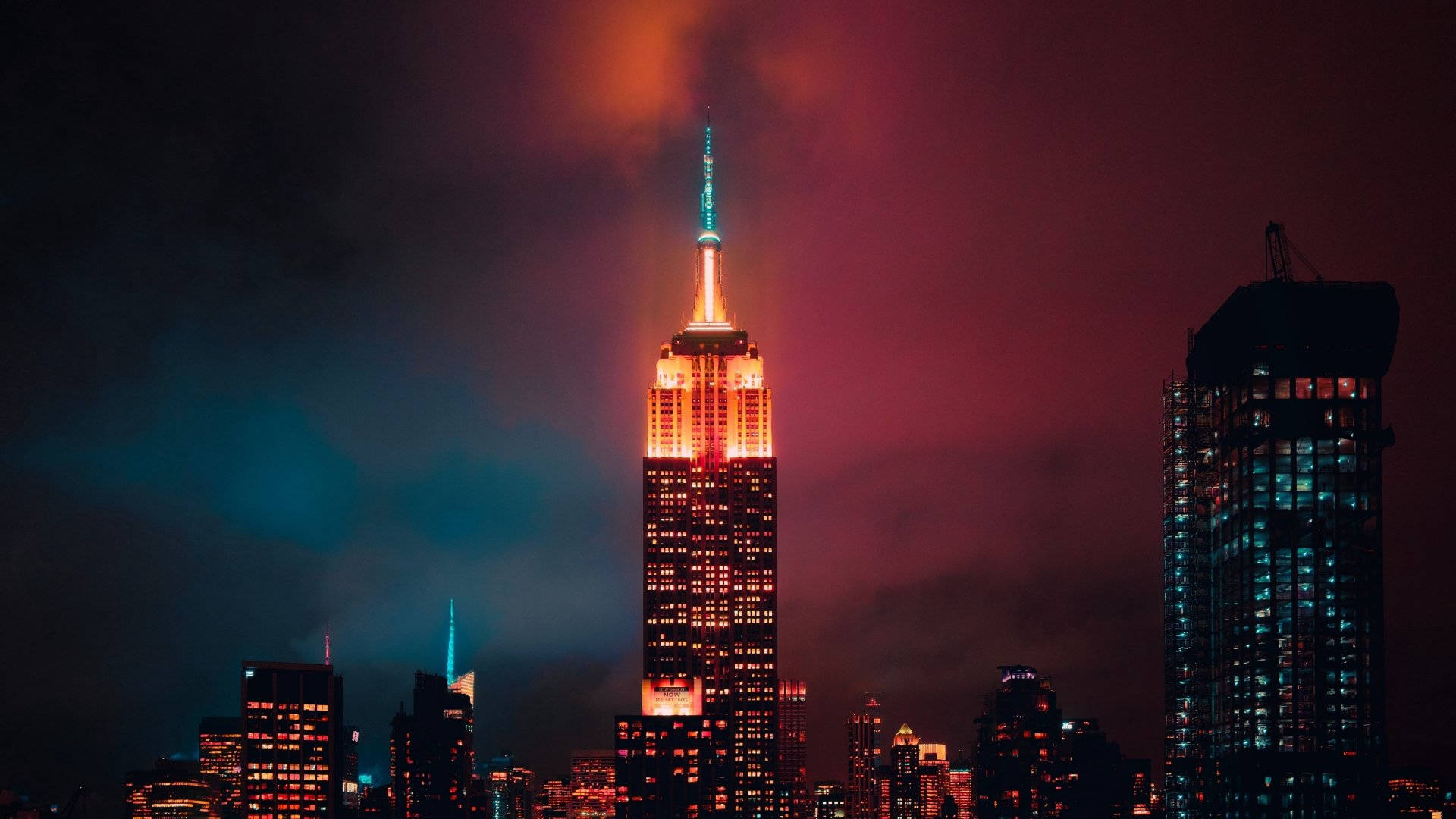 empire 桌布 壁紙 — 帝國大廈在佈滿粉紅和青綠色雲彩的戲劇性暮色天空中溫暖地發光。