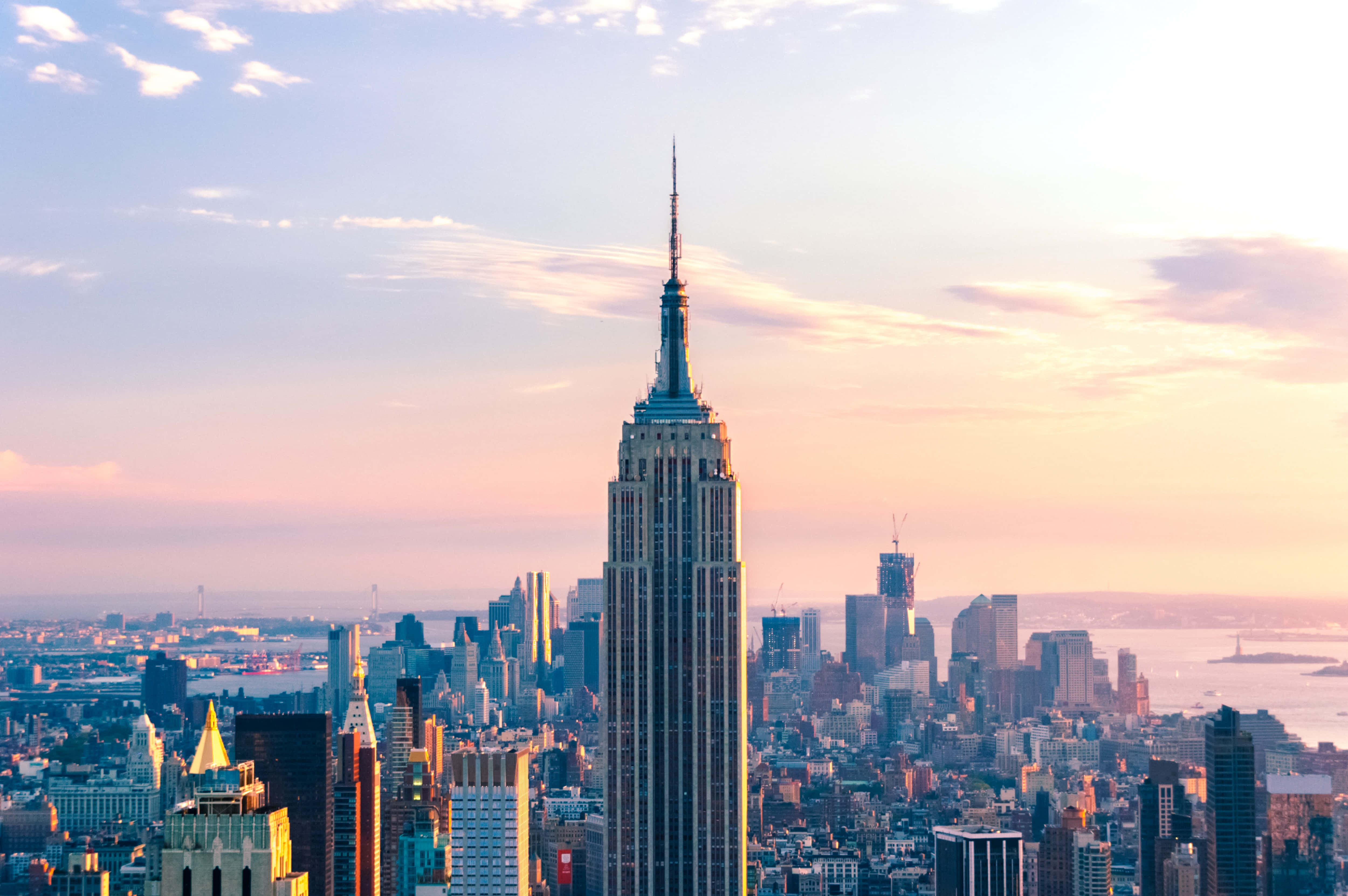 Empire State Building 桌布 壁紙 — 帝國大廈在日落時分聳立於紐約市上空，溫暖的金色光芒沐浴著天際線和雲層。