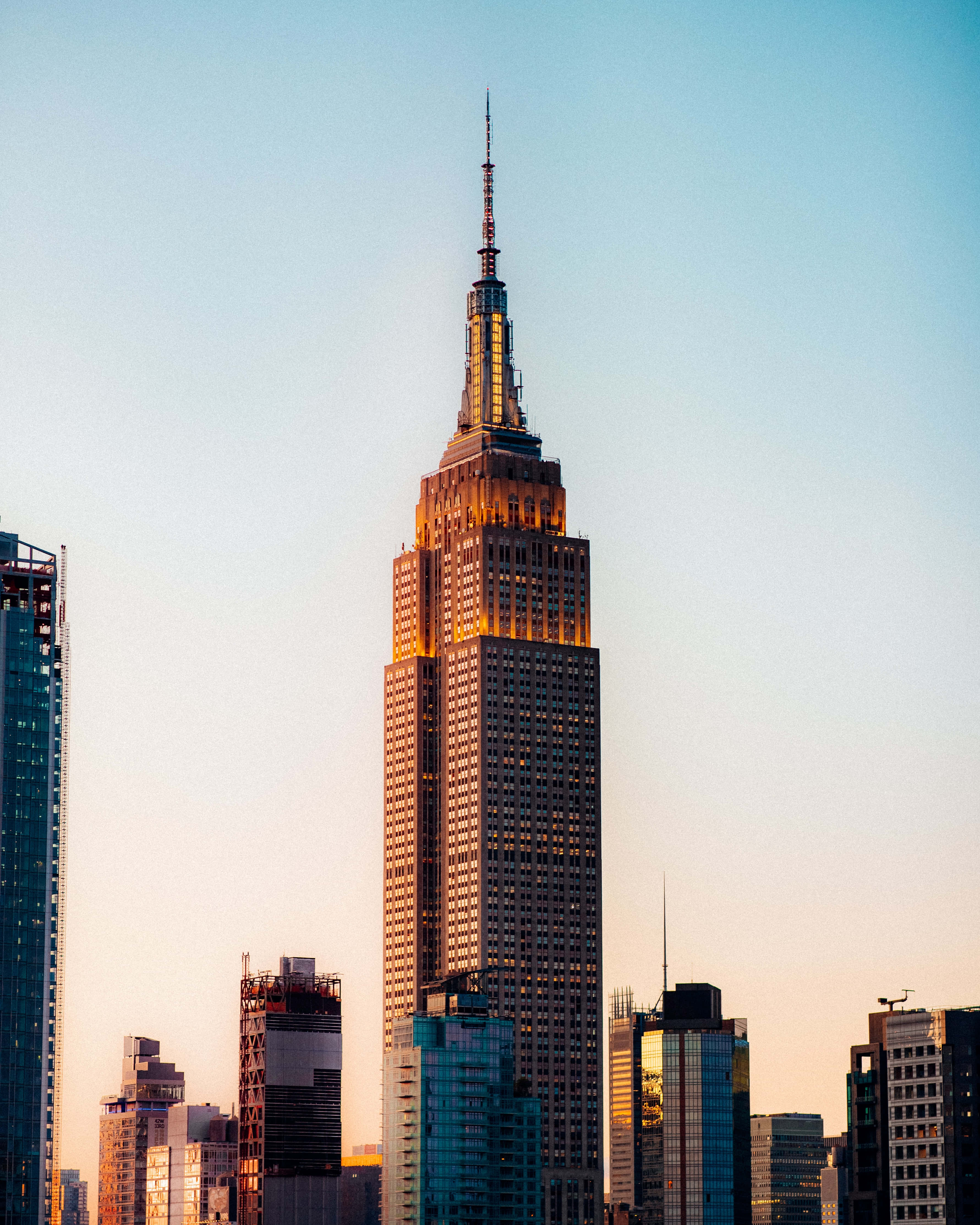 Empire State Building 桌布 壁紙 — 帝國大廈在日落時分聳立於紐約市上空，金色的燈光在柔和的藍天下閃耀。