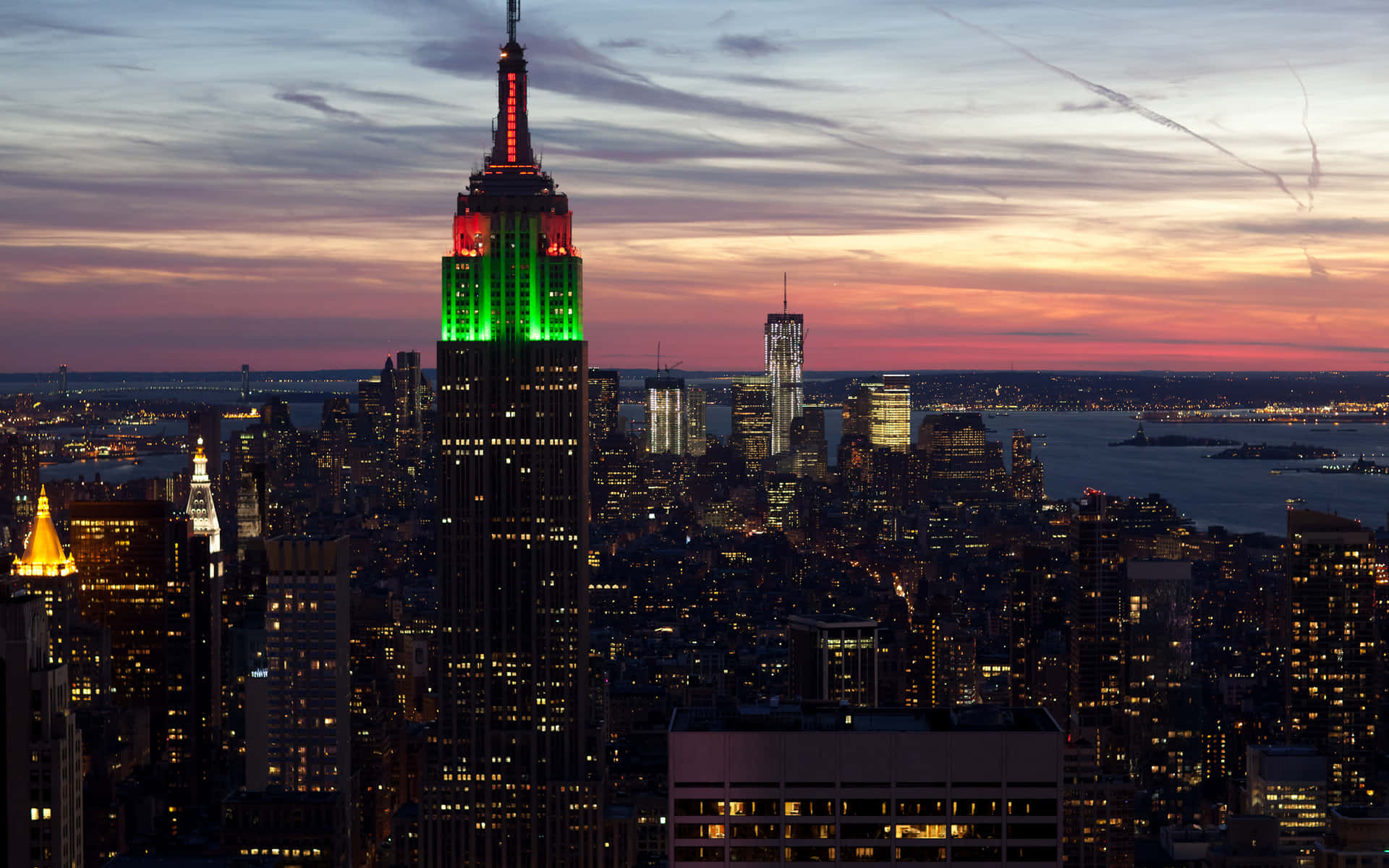 Empire State Building 桌布 壁紙 — 帝國大廈在暮色天空中發出綠色光芒，而紐約市的燈光在下方亮起。