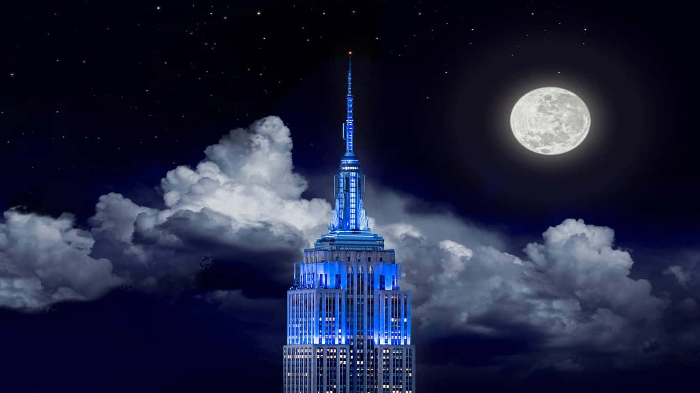 1366x768 Empire State Building 桌布 壁紙 — 帝國大廈在滿月和戲劇性雲層的星空夜空下發出藍色光芒。