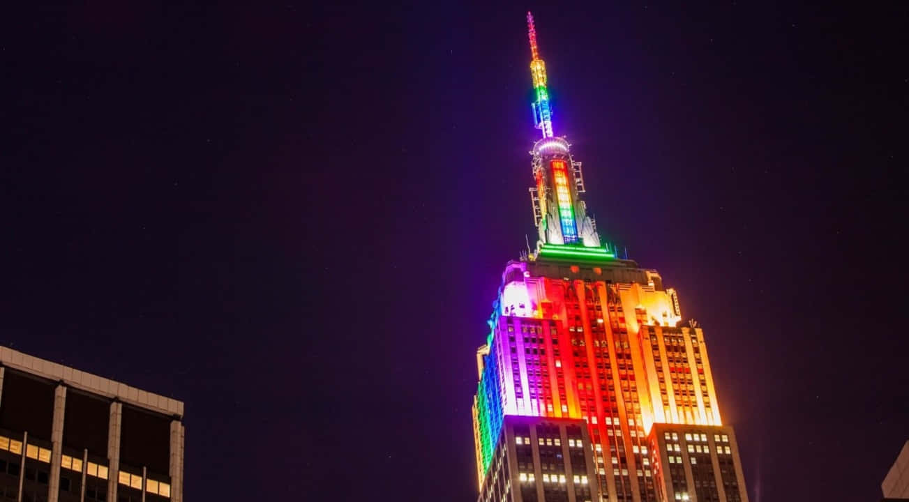720p Empire State Building 桌布 壁紙 — 帝國大廈在漆黑的夜空下閃耀著鮮豔的彩虹燈光，構成引人注目的城市夜景。