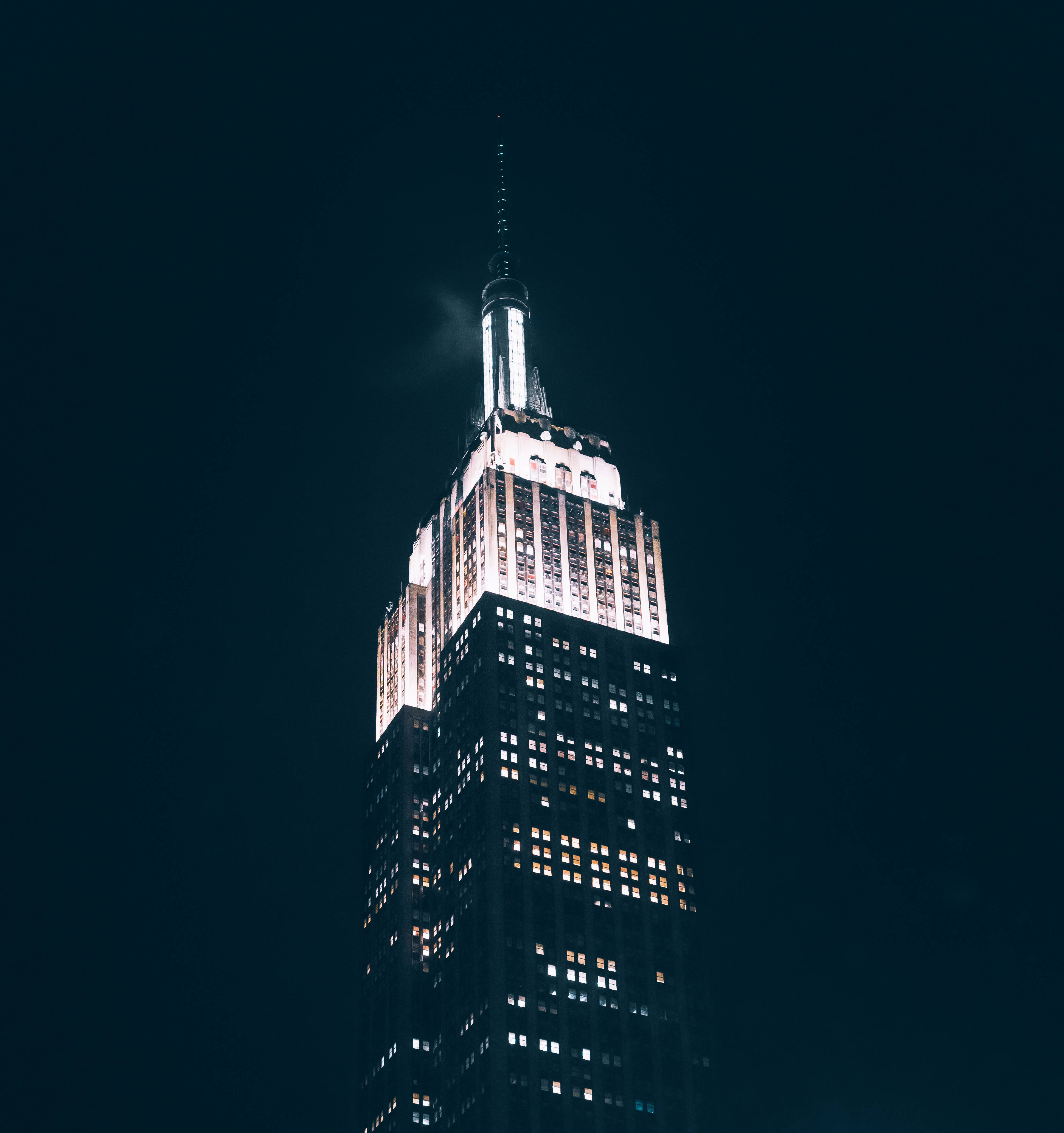 Skyscraper 桌布 壁紙 — 帝國大廈在漆黑的夜空中高聳入雲，其發光的尖頂和窗戶閃爍著溫暖的光芒。