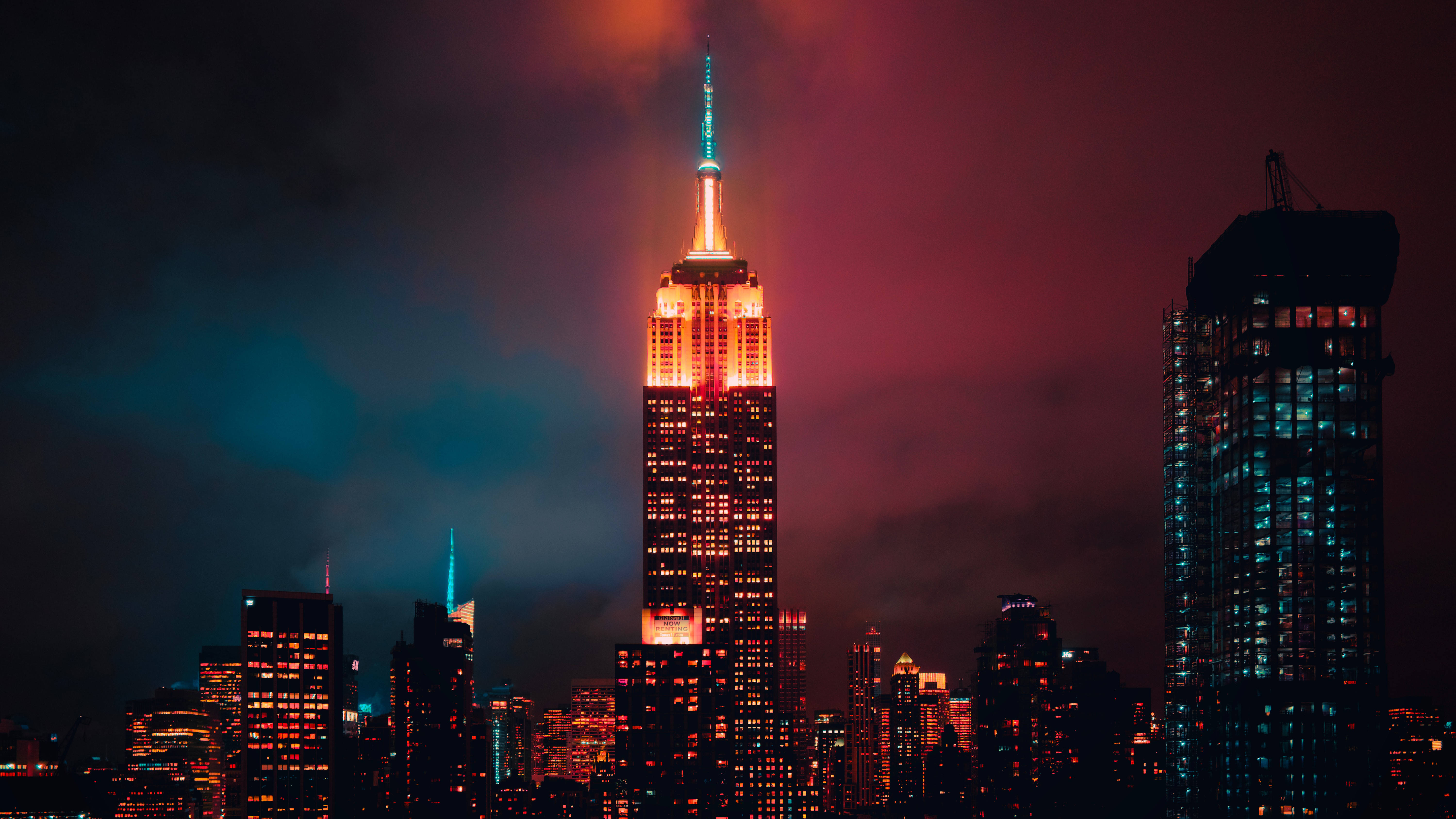 empire state 桌布 壁紙 — 帝國大廈在琥珀色和藍綠色的光芒中，映襯著帶有洋紅色和藍綠色雲彩的戲劇性暮色天空。