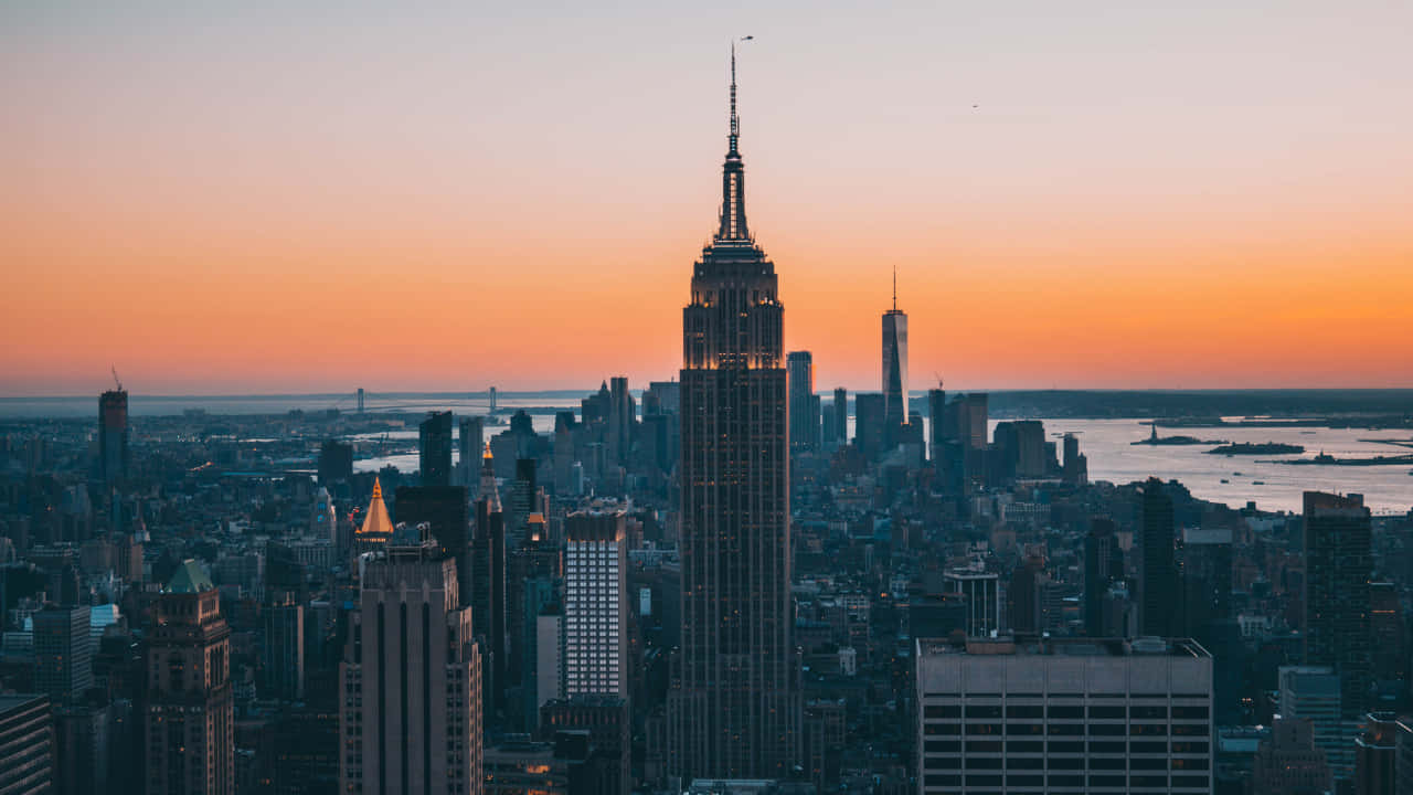 720p Ny City 桌布 壁紙 — 帝國大廈在紐約市天際線上，聳立在充滿活力的橙色日落天空前。