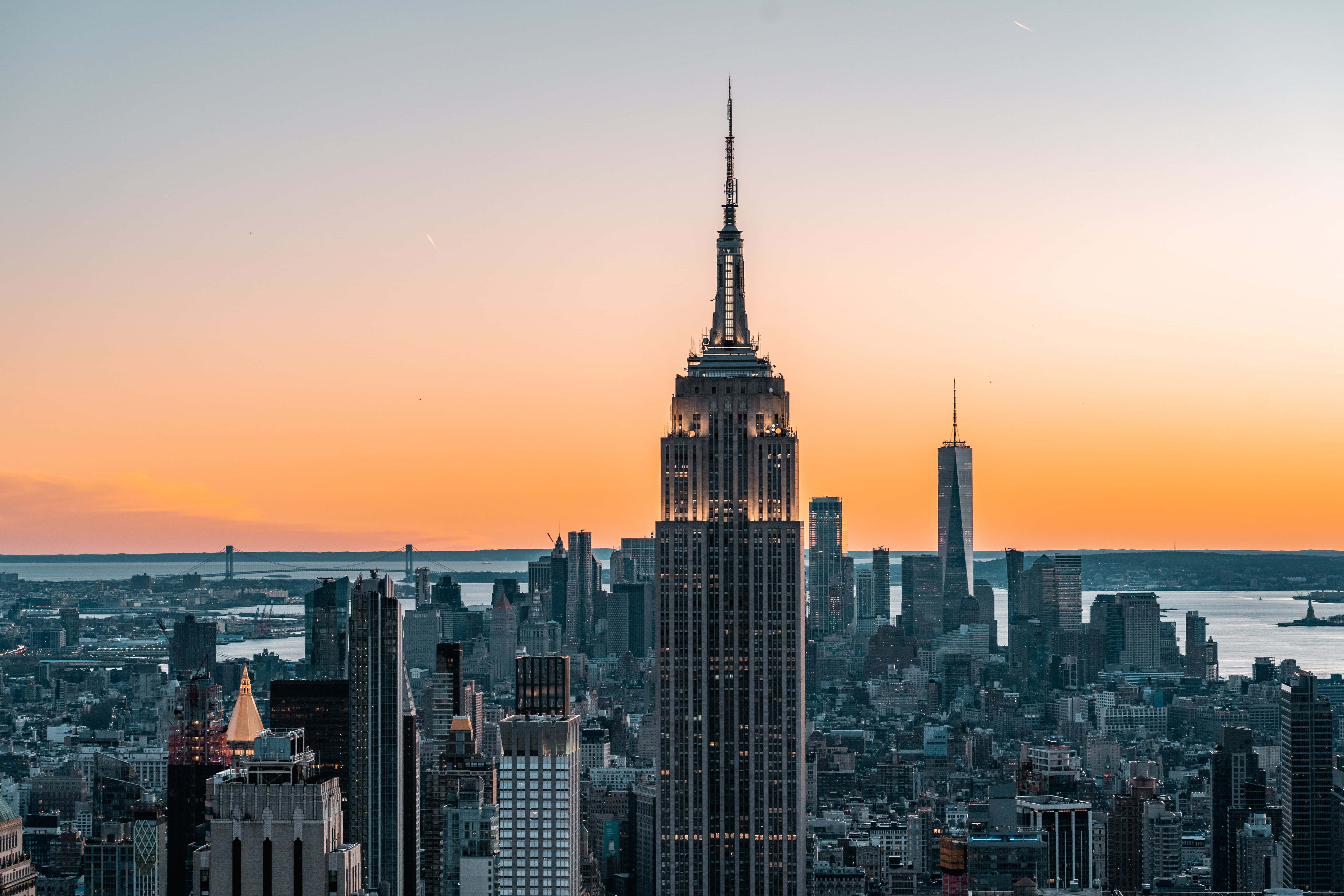 Empire State Building 桌布 壁紙 — 帝國大廈在紐約市天際線上方，襯著鮮豔的橙色日落天空高聳入雲。