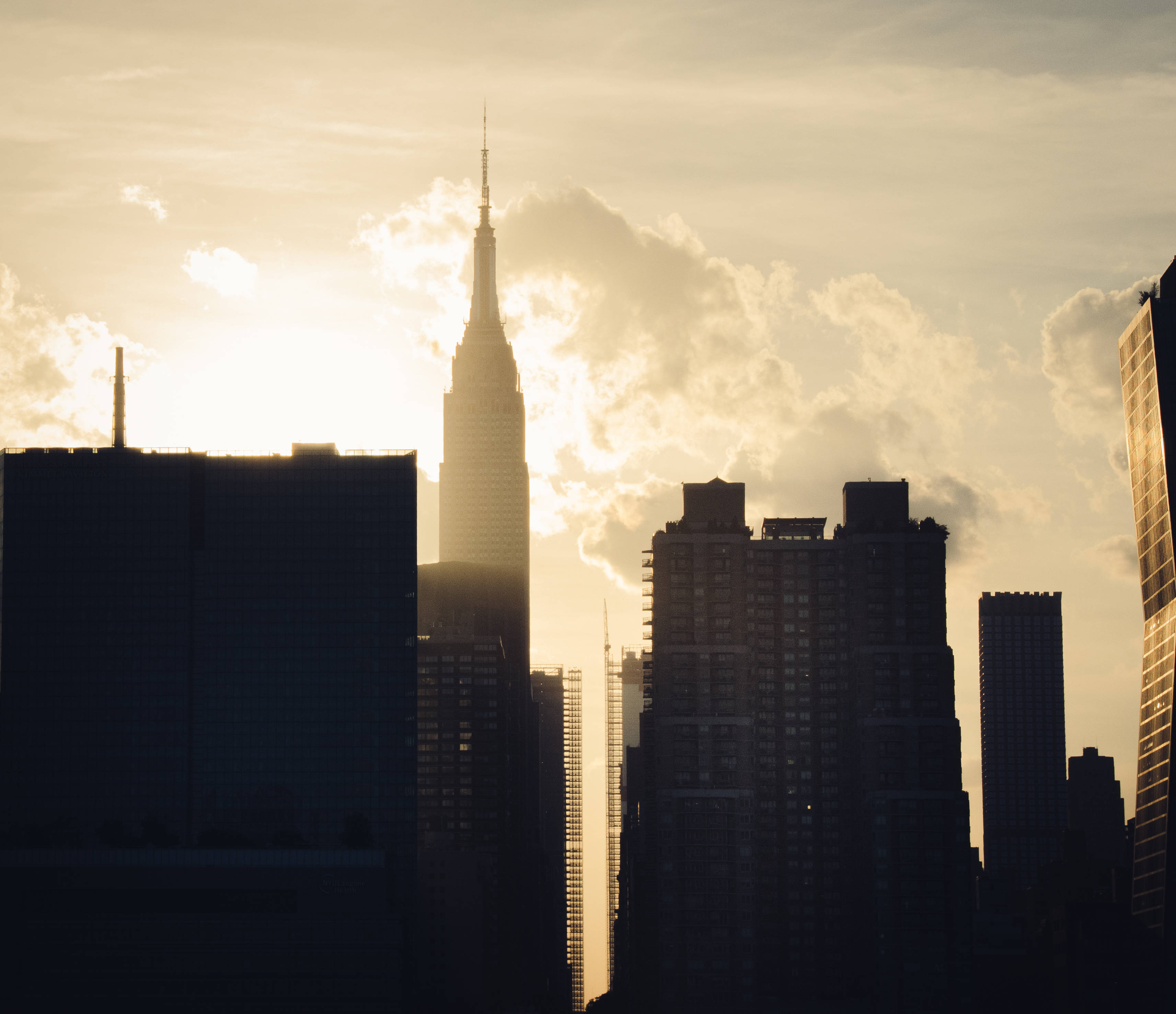 Skyscraper 桌布 壁紙 — 帝國大廈在金色日落天空與散雲的襯托下，以剪影姿態高聳矗立。