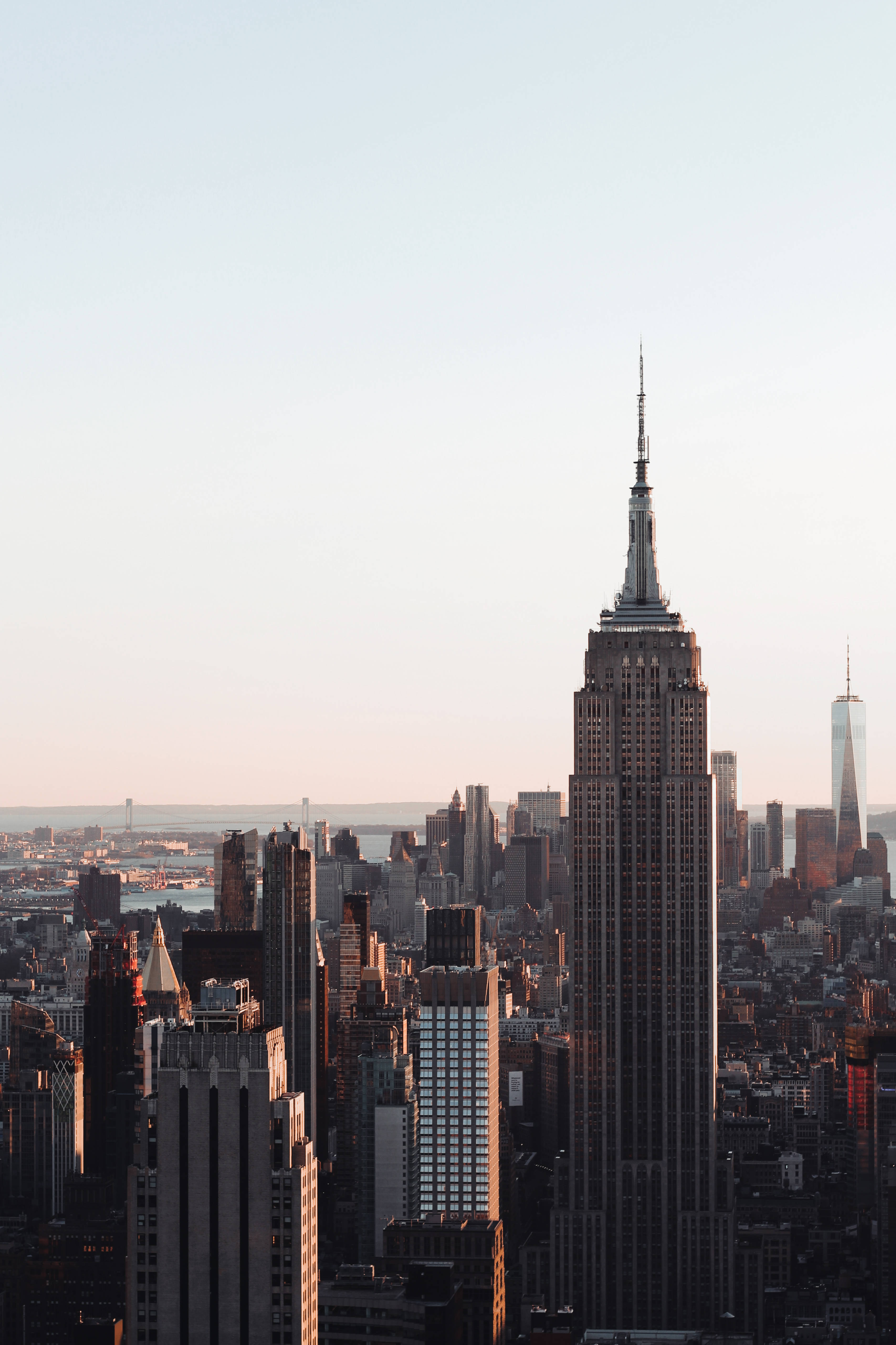 Nyc Aesthetic 桌布 壁紙 — 帝國大廈在黃金時刻聳立於密集的紐約市天際線之上，伴隨著柔和粉彩的天空。