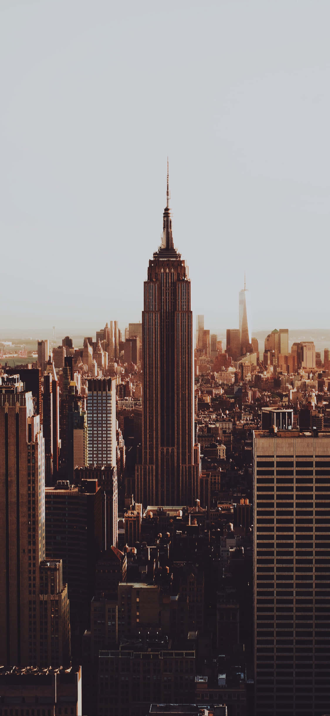 New York 桌布 壁紙 — 帝國大廈聳立在沐浴在溫暖金色時刻光線中的密集紐約市天際線之上。