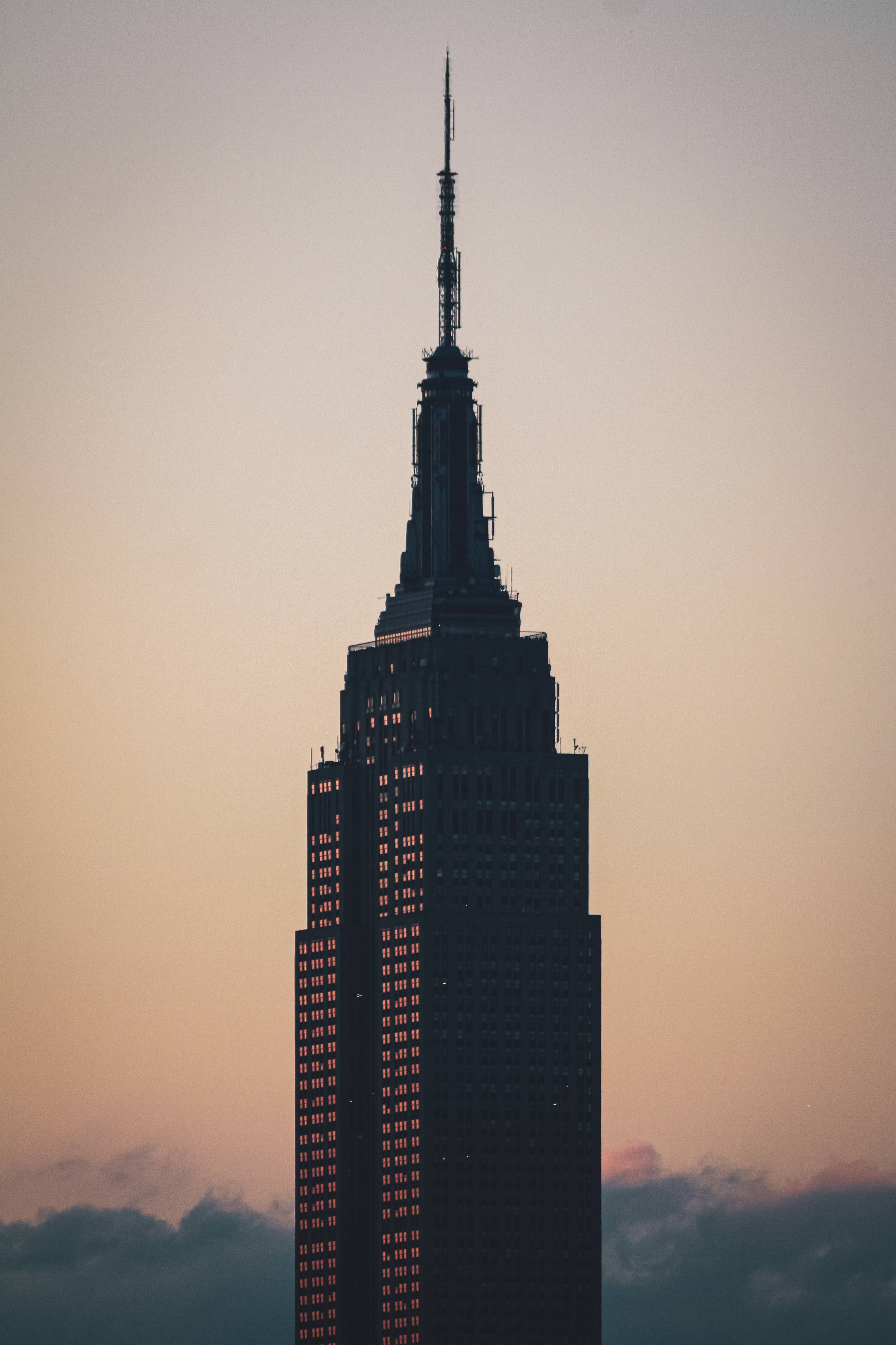 Skyscraper 桌布 壁紙 — 帝國大廈高聳入雲，下方是柔和的粉紅色和橙色暮色天空，雲朵在下方。