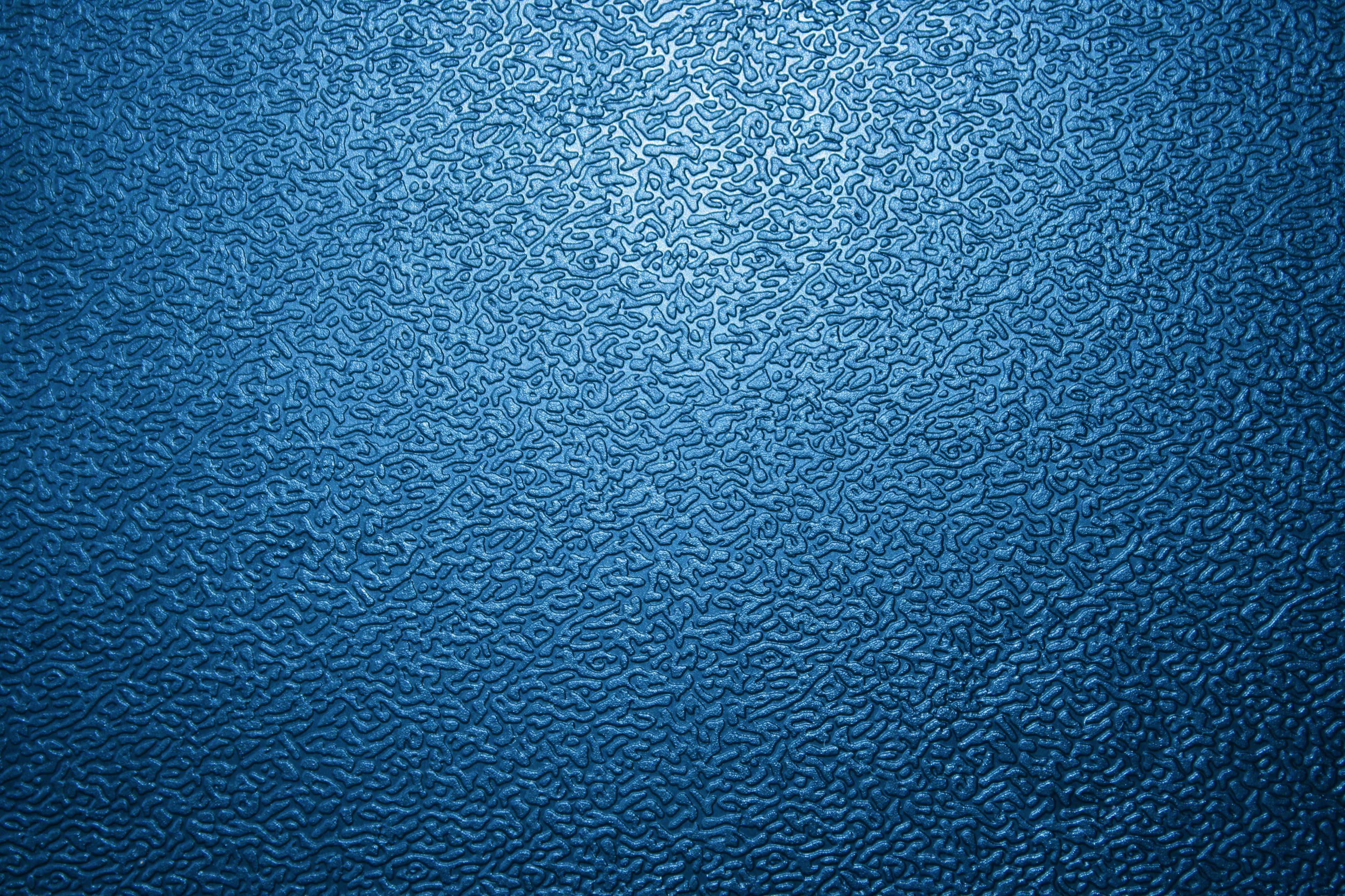Metal Texture 桌布 壁紙 — 帶有從中心輻射的漸變光效的紋理藍色表面的特寫。