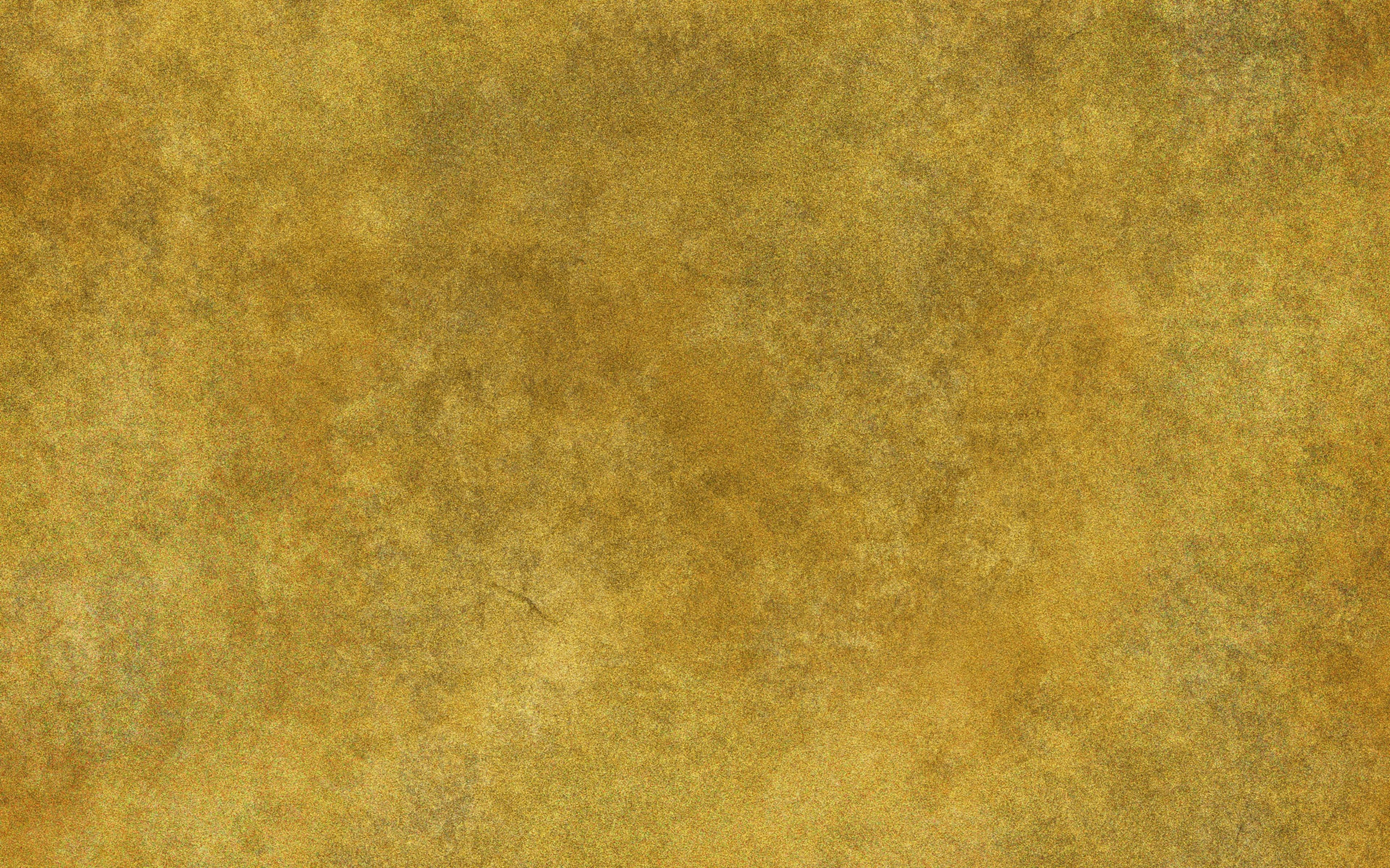 Yellow Grunge 桌布 壁紙 — 帶有斑駁棕色和灰色變化的紋理金黃色表面，類似於陳舊的羊皮紙或金屬箔。