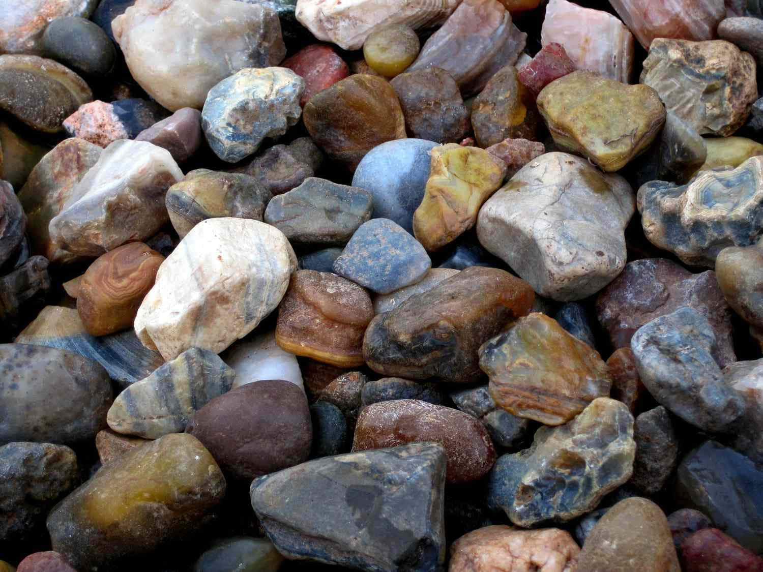 Gemstone 桌布 壁紙 — 平滑河石的近距離特寫，呈現大地色調、多樣紋理和自然圖案。