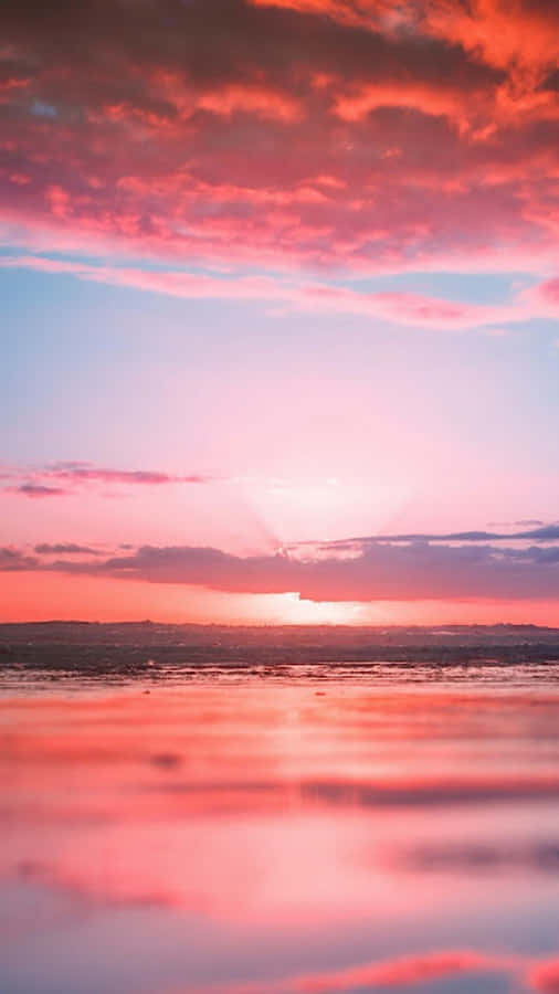 桌布 壁紙 — 平靜水面上夕陽西下，火紅粉紅雲彩倒映在平靜水面。