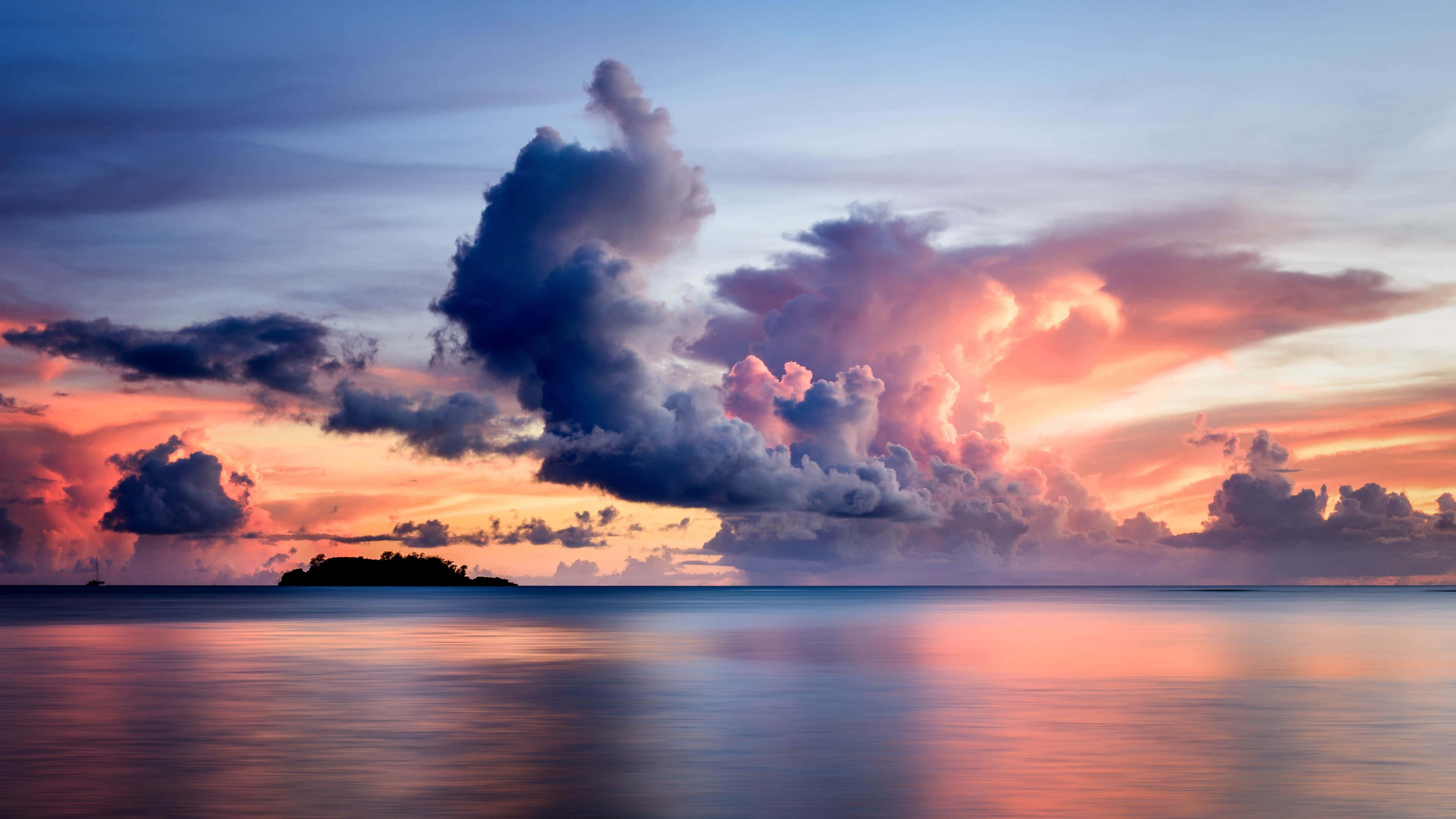 Clouds Aesthetics 桌布 壁紙 — 平靜水面上寧靜的日落，小島的剪影，以及火橙色和深藍色調繪製的戲劇性雲彩。