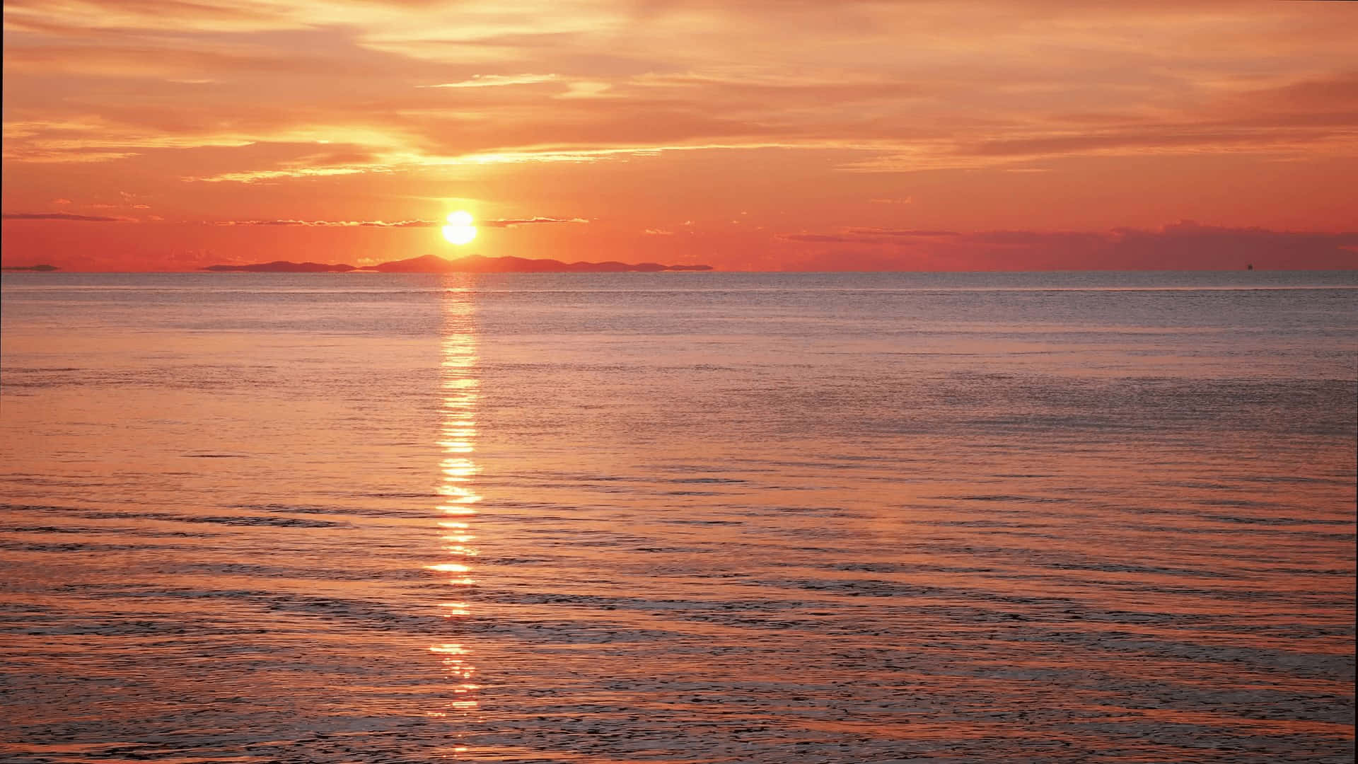 Sunset Reflection 桌布 壁紙 — 平靜海面上令人屏息的日落，燦爛的金色太陽在水面投射出一條閃爍的光路。