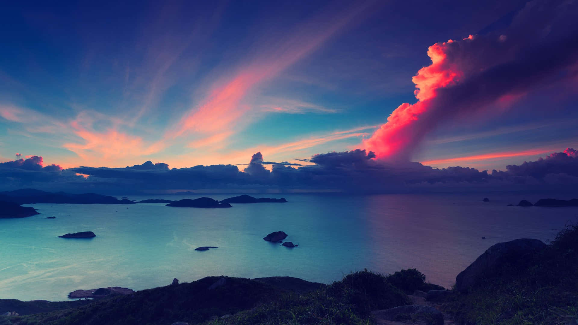 Aesthetic Sunset 桌布 壁紙 — 平靜海面上令人驚嘆的日落，充滿活力的粉紅色和紫色雲彩倒映在水面和遠處的島嶼上。