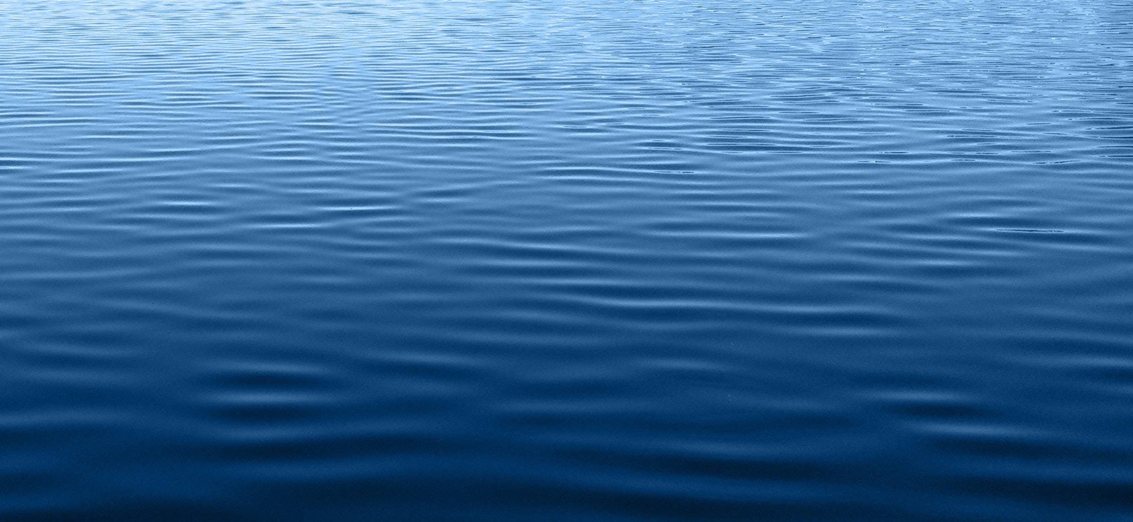 水 桌布 壁紙 — 平靜深藍色水在柔和光線下輕輕泛起漣漪，營造出寧靜祥和的自然景象。