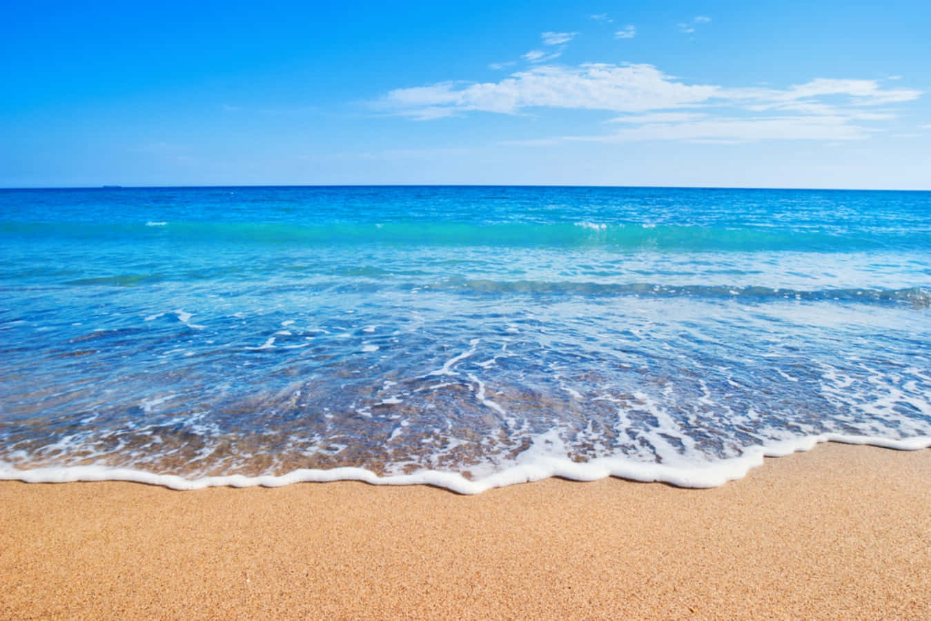 sand 桌布 壁紙 — 平靜的藍綠色海浪輕輕地拍打著金色的沙灘，天空湛藍，飄著幾縷薄雲。