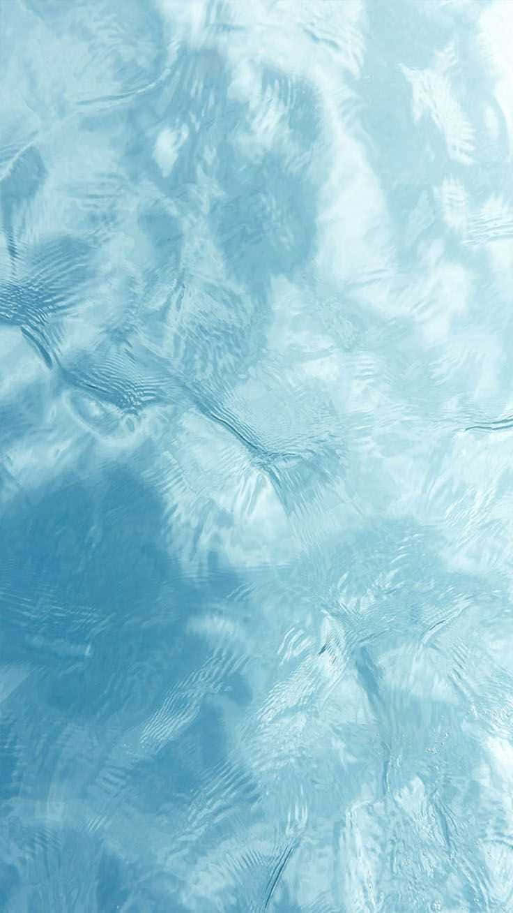 Light Blue Marble 桌布 壁紙 — 平靜的近距離特寫，呈現漣漪的淺藍色水面，帶有柔和波浪紋理和柔軟反射。