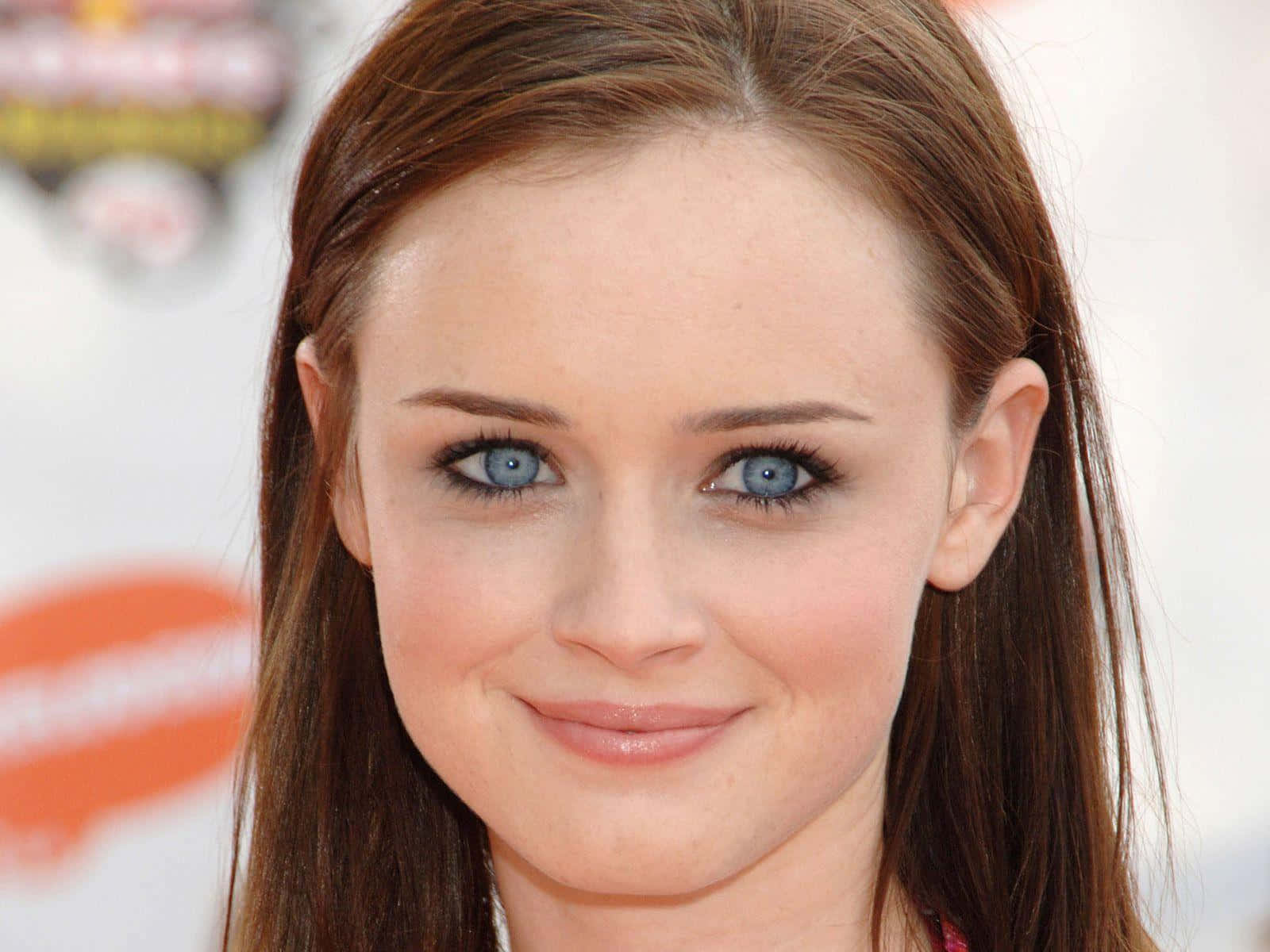 Alexis Bledel 桌布 壁紙 — 年輕女性的特寫肖像，她有搶眼的藍眼睛和棕色頭髮，輕輕對著鏡頭微笑。