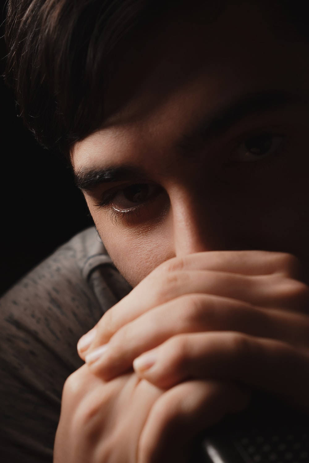 Eyes 桌布 壁紙 — 年輕男子在昏暗燈光下用手摀住嘴巴，眼神強烈的特寫。