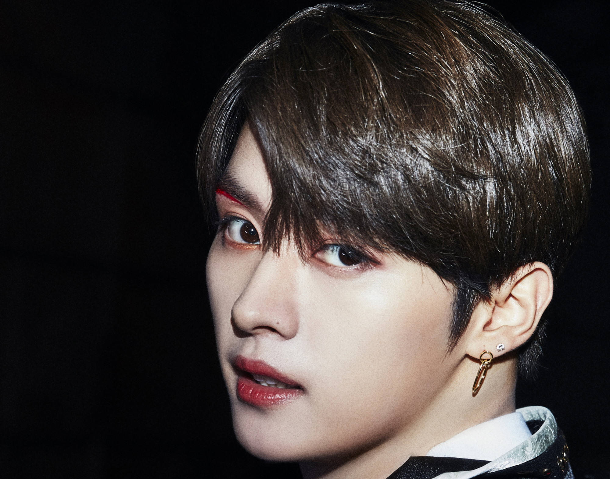 Stray Kids 桌布 壁紙 — 年輕男子特寫肖像，深色頭髮，紅色眼線，金色耳環，黑色背景。
