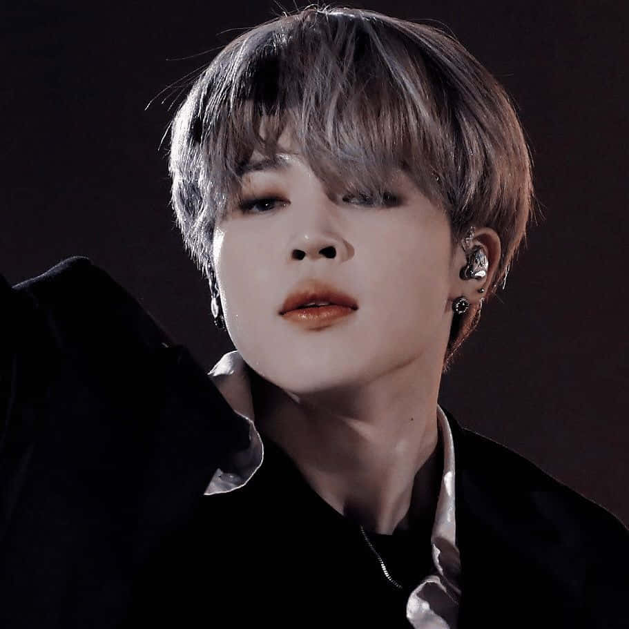 Jimin Aesthetic 桌布 壁紙 — 年輕男子的特寫肖像，他有短層次頭髮和多個耳環，背景是深色。
