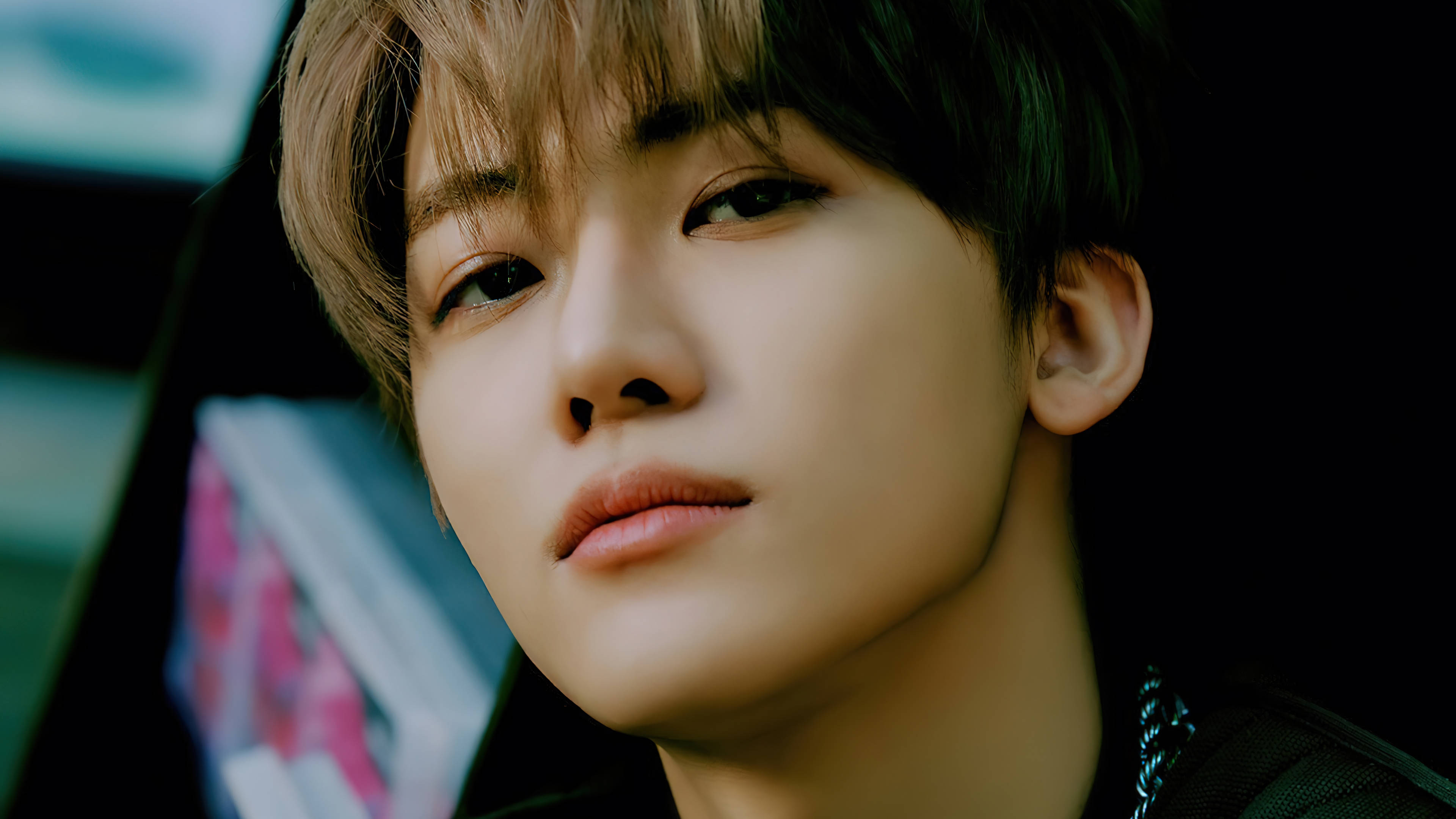 jaemin 桌布 壁紙 — 年輕男子的特寫肖像，柔和光線和模糊背景展現鮮豔色彩。