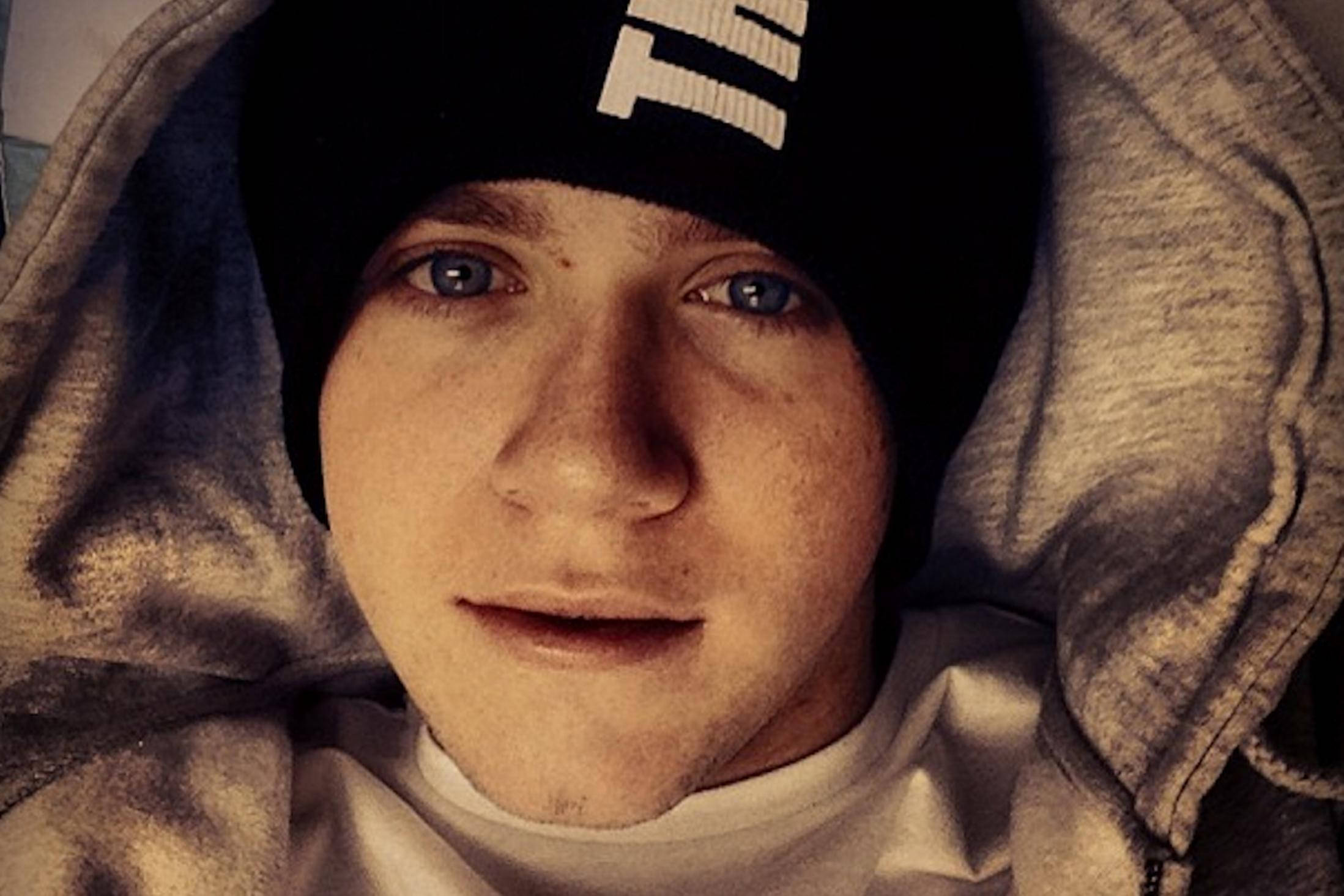 niall horan 桌布 壁紙 — 年輕男子近照，臉上有雀斑，藍色眼睛，戴黑色毛帽和連帽上衣，直視鏡頭。