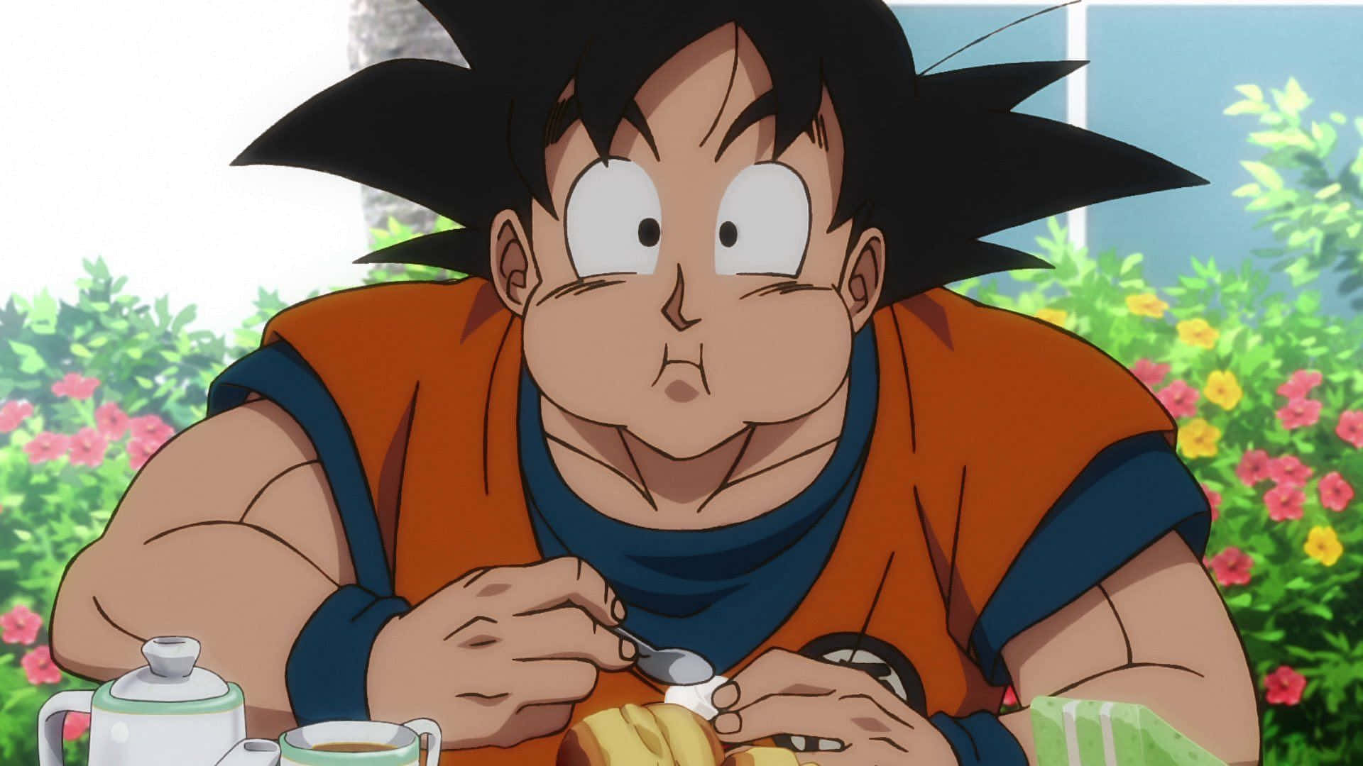Funny Goku 桌布 壁紙 — 年輕的悟空坐在桌子旁吃早餐，表情驚訝，周圍是色彩繽紛的花朵。