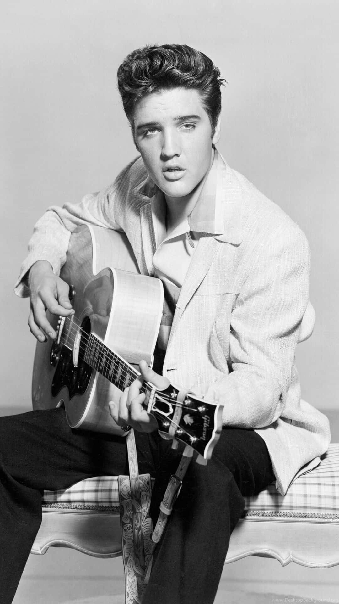 4K Elvis 桌布 壁紙 — 年輕的貓王埃爾維斯·普雷斯利坐著，手持一把木吉他，經典黑白工作室肖像。