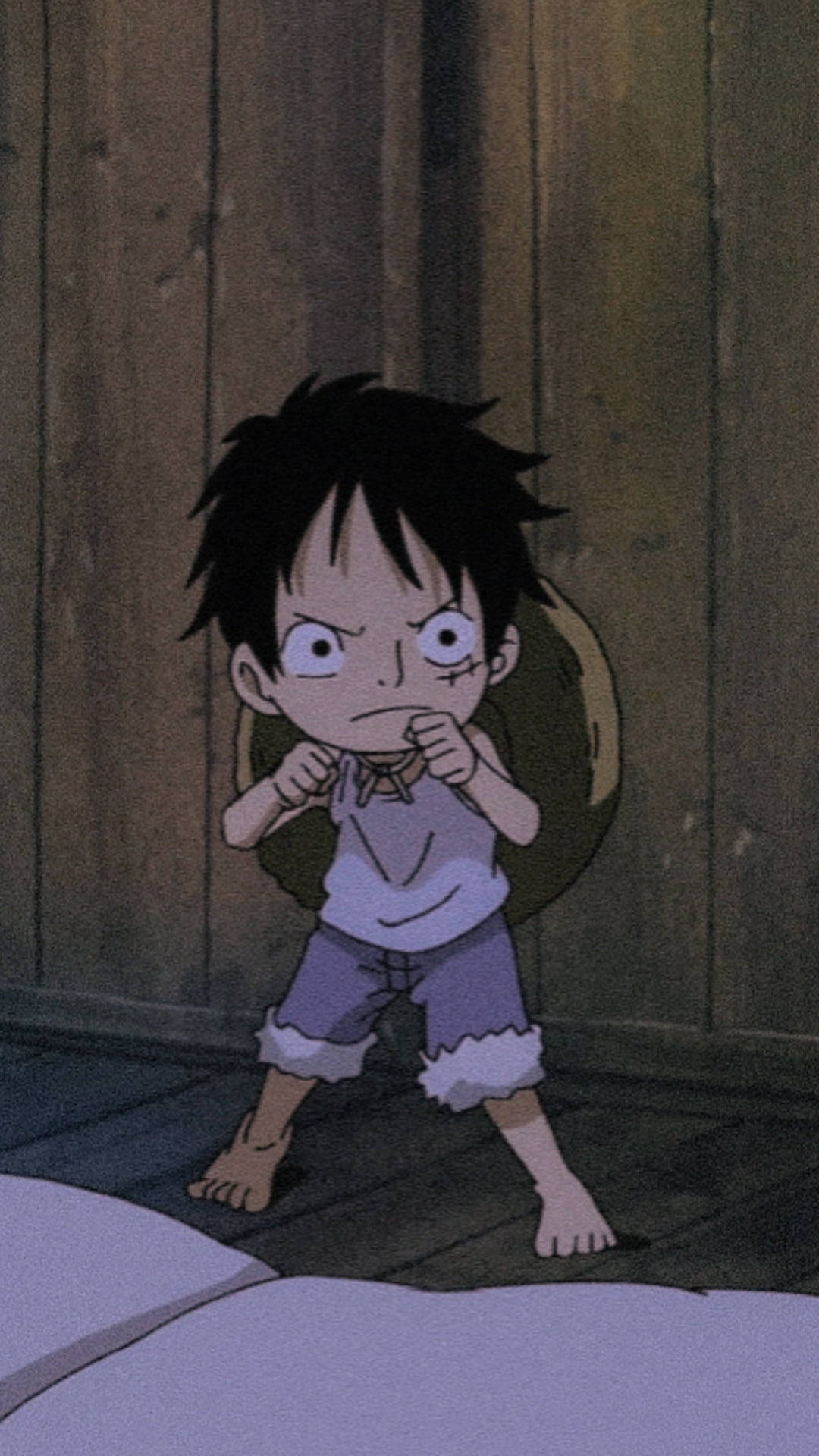 Luffy 桌布 壁紙 — 年輕的魯夫在昏暗的木房間中堅定地站著，抓住他的襯衫，表情兇猛。