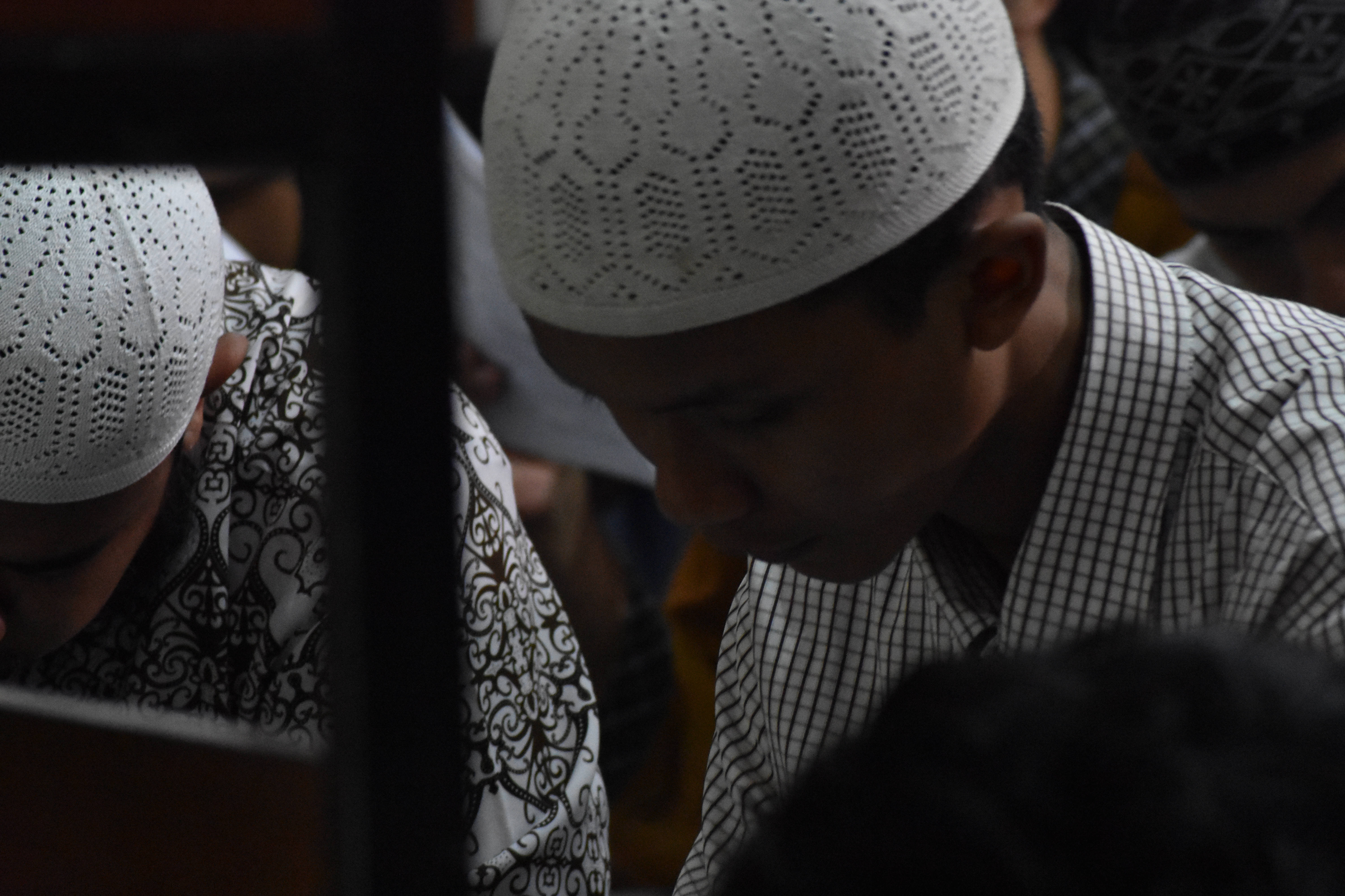 Ramadan 桌布 壁紙 — 年輕穆斯林男子戴著白色祈禱帽在宗教聚會中莊嚴鞠躬敬拜的特寫。