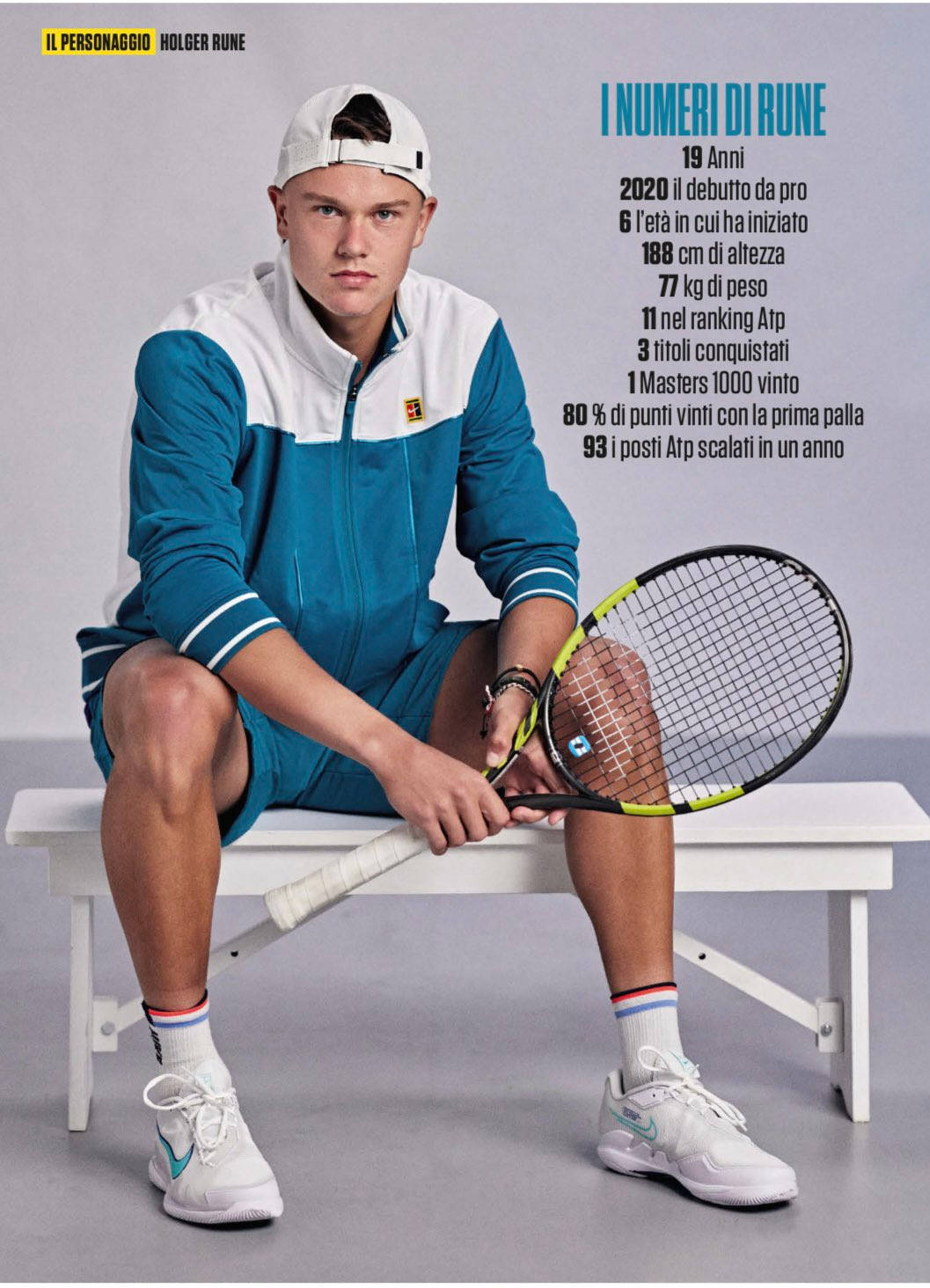 Tennis 桌布 壁紙 — 年輕網球選手霍爾格·魯尼坐在白色長椅上，手持球拍，背景為純灰色，旁邊有統計文字。
