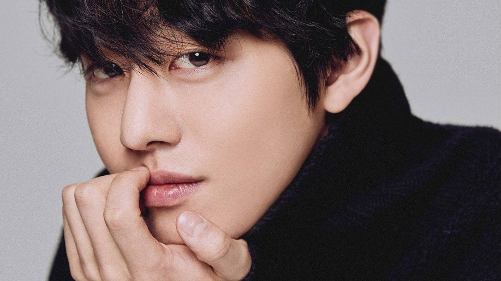 Ahn Hyo Seop 桌布 壁紙 — 年輕黑髮男子的特寫肖像，他托著下巴，眼神若有所思，背景是柔和灰色。