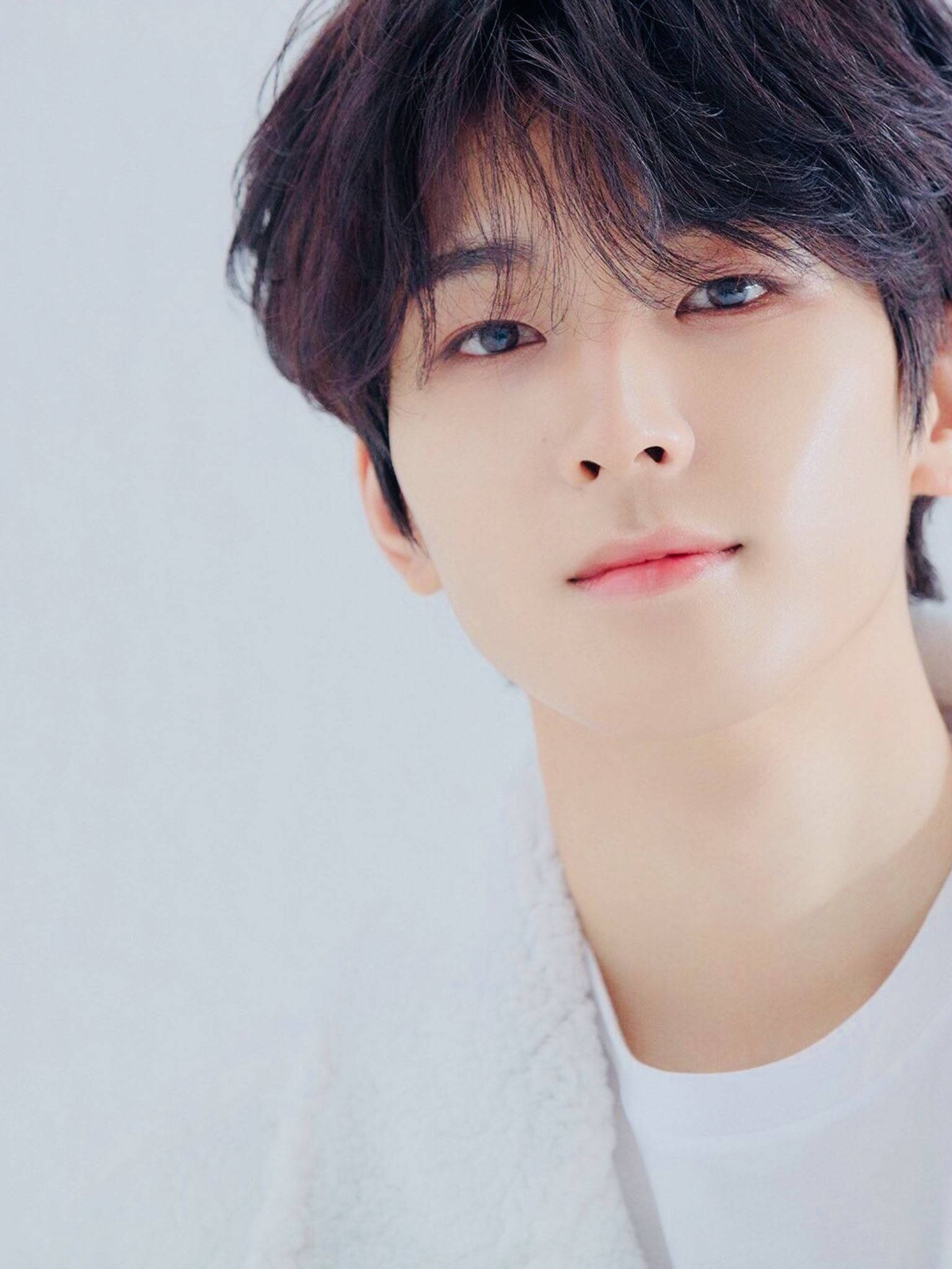원우 桌布 壁紙 — 年輕黑髮男子近距離肖像，柔和藍色眼睛，在純白背景前溫柔凝視。