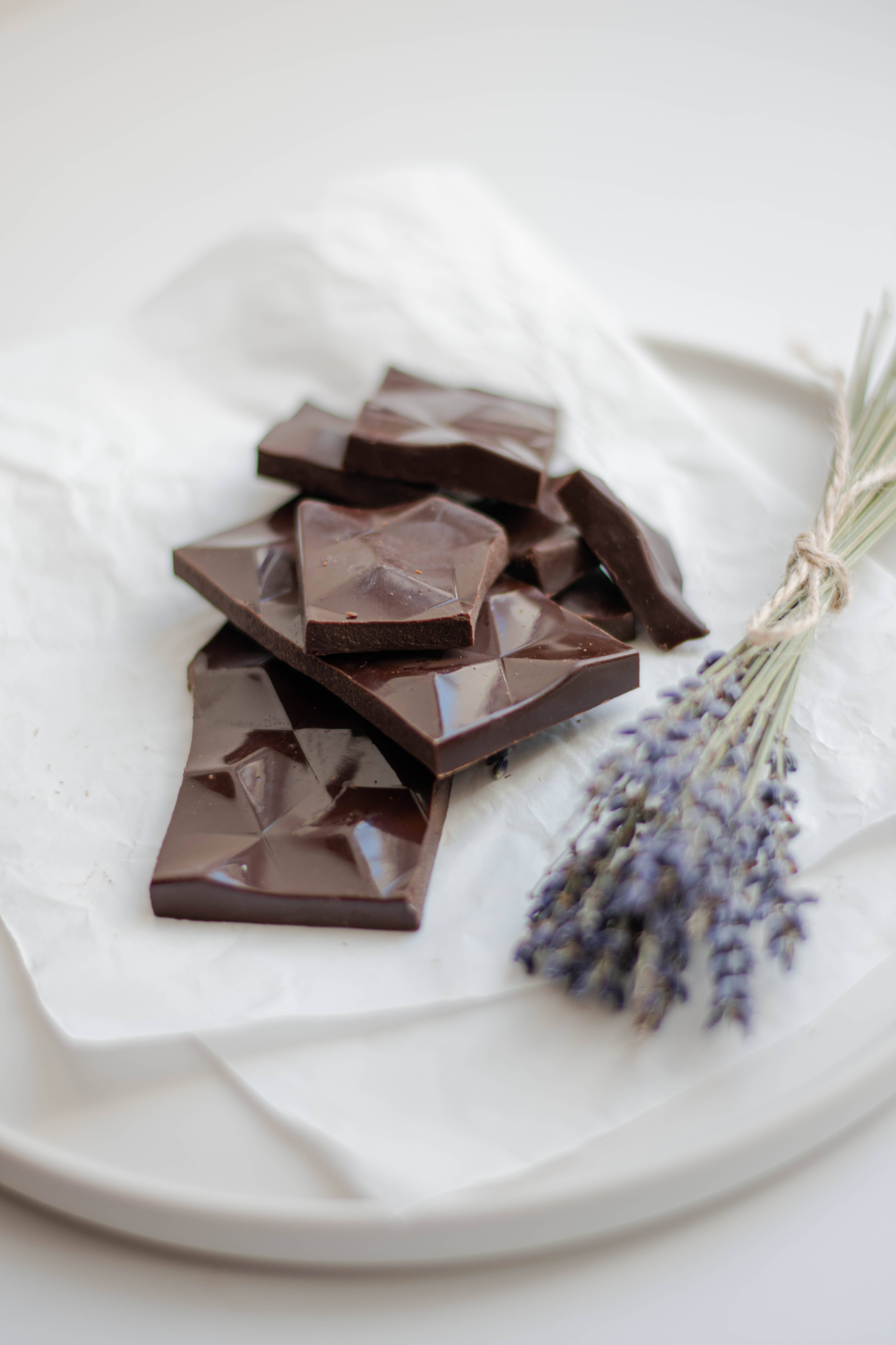 Chocolate 桌布 壁紙 — 幾何形狀的黑巧克力碎片和薰衣草枝條放在白色盤子上的皺白紙上。