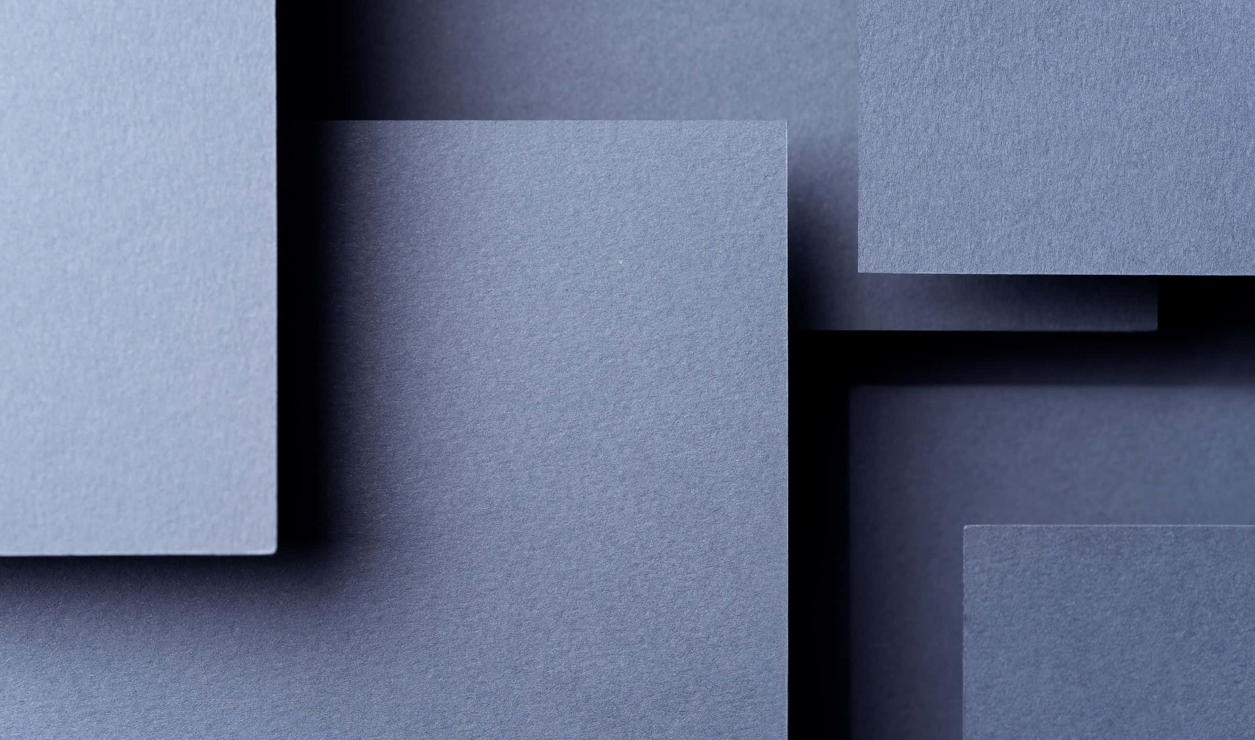 2440x1440 Material 桌布 壁紙 — 幾何排列的紋理藍灰色紙張，在極簡構圖中投射出柔和陰影。