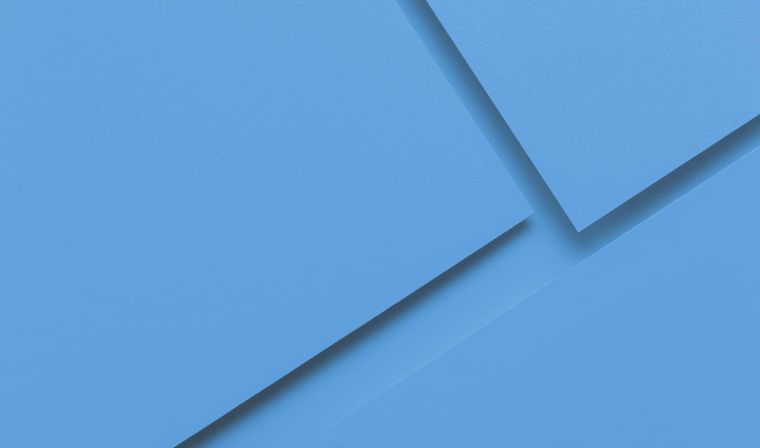 2440x1440 Material 桌布 壁紙 — 幾何藍色面板在柔和陰影中重疊，營造出極簡抽象構圖。