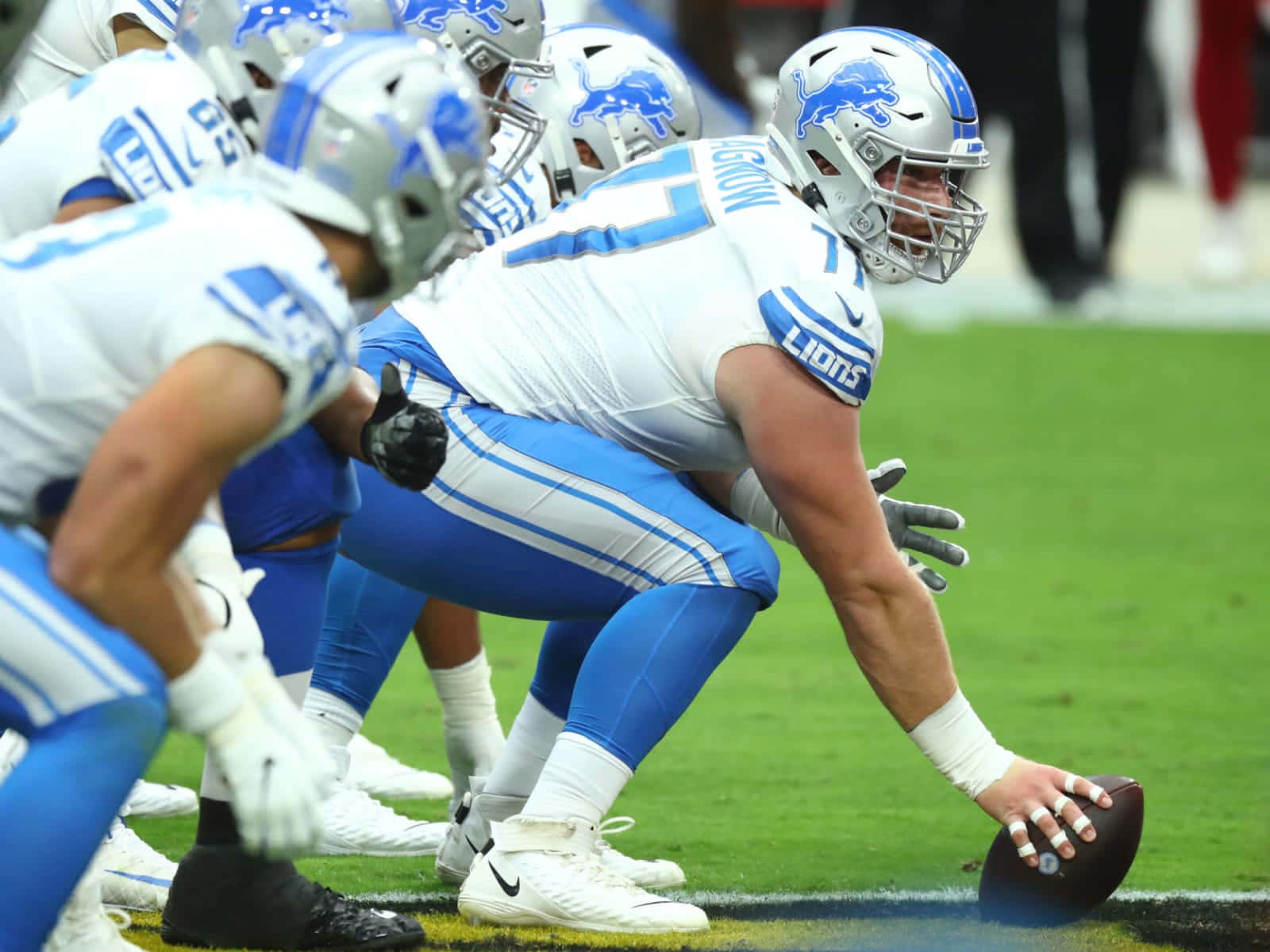 底特律雄獅 桌布 壁紙 — 底特律雄獅隊的一名進攻鋒線球員在NFL比賽中蹲低身體，手持橄欖球準備開球。