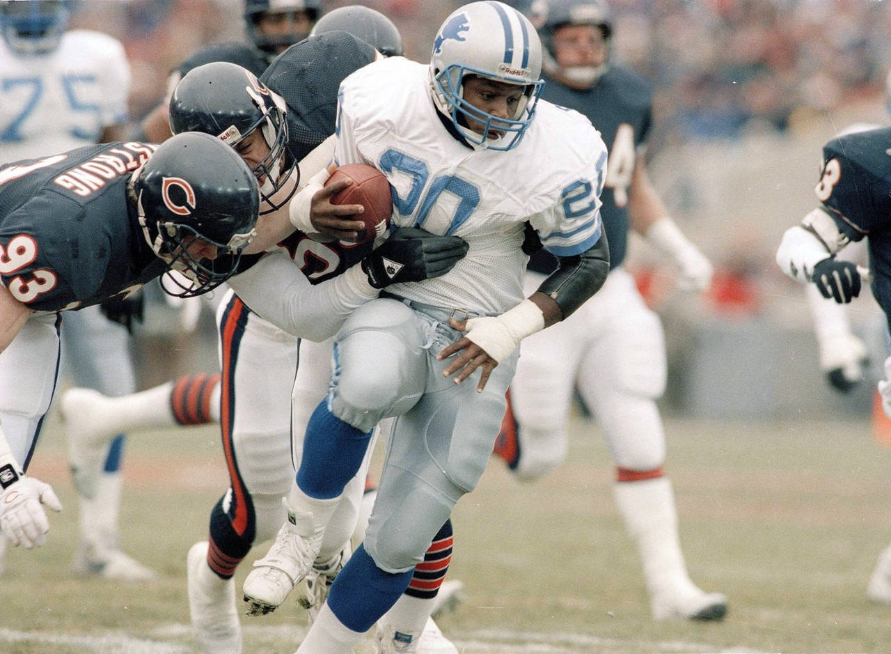 Barry Sanders 桌布 壁紙 — 底特律雄獅隊的跑衛身穿白色球衣，在草地場上激烈的NFL比賽中突破芝加哥熊隊的擒抱。