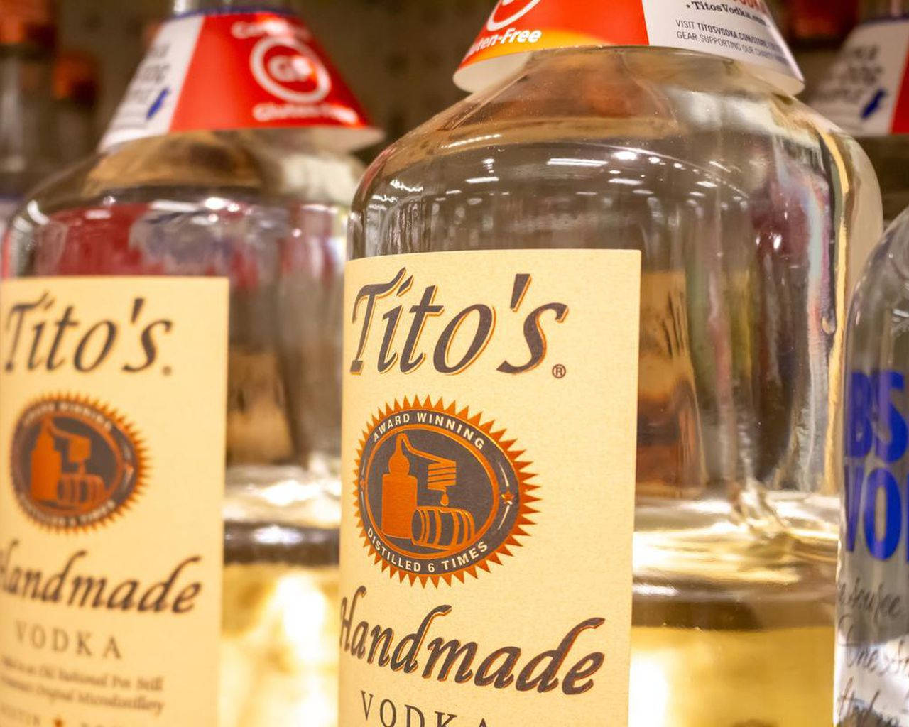 標誌 桌布 壁紙 — 店鋪貨架上Tito's Handmade Vodka酒瓶的特寫，帶有琥珀色標籤和紅色瓶蓋。