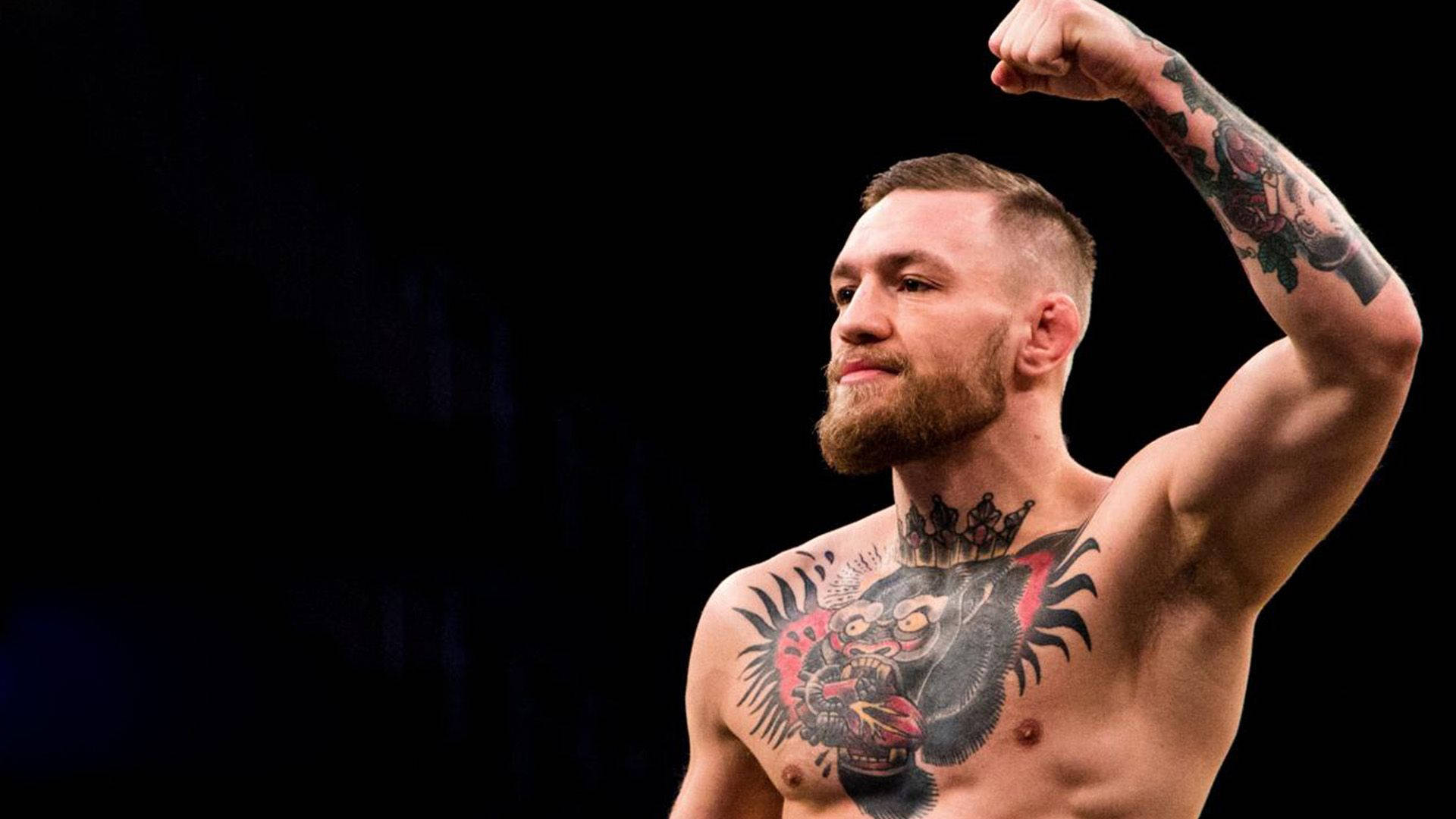 Mcgregor 桌布 壁紙 — 康納·麥格雷戈在深色背景下彎曲他紋身的手臂，露出勝利的表情。