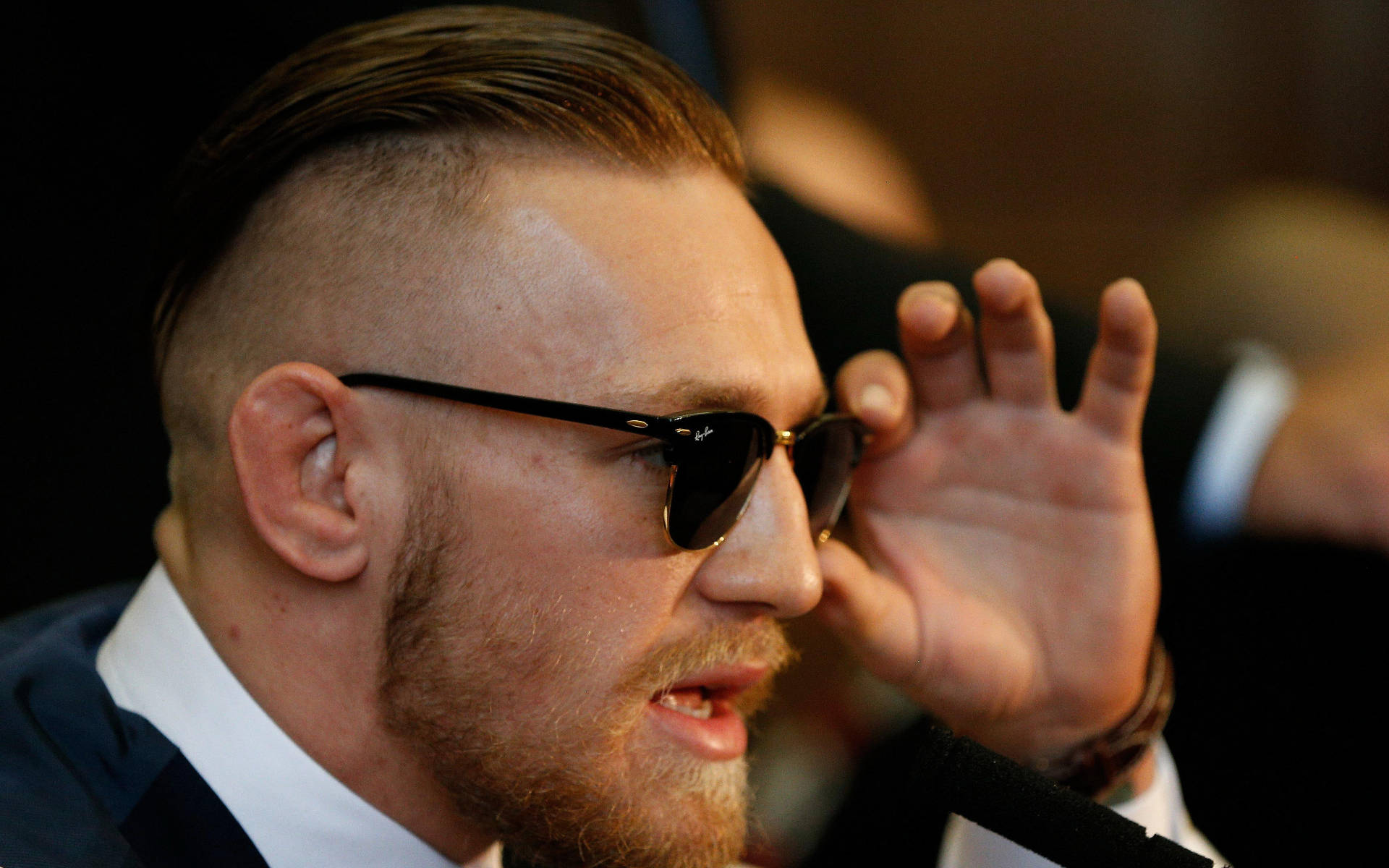 Mcgregor 桌布 壁紙 — 康納·麥格雷戈身穿俐落西裝，在記者會上自信地調整太陽眼鏡。
