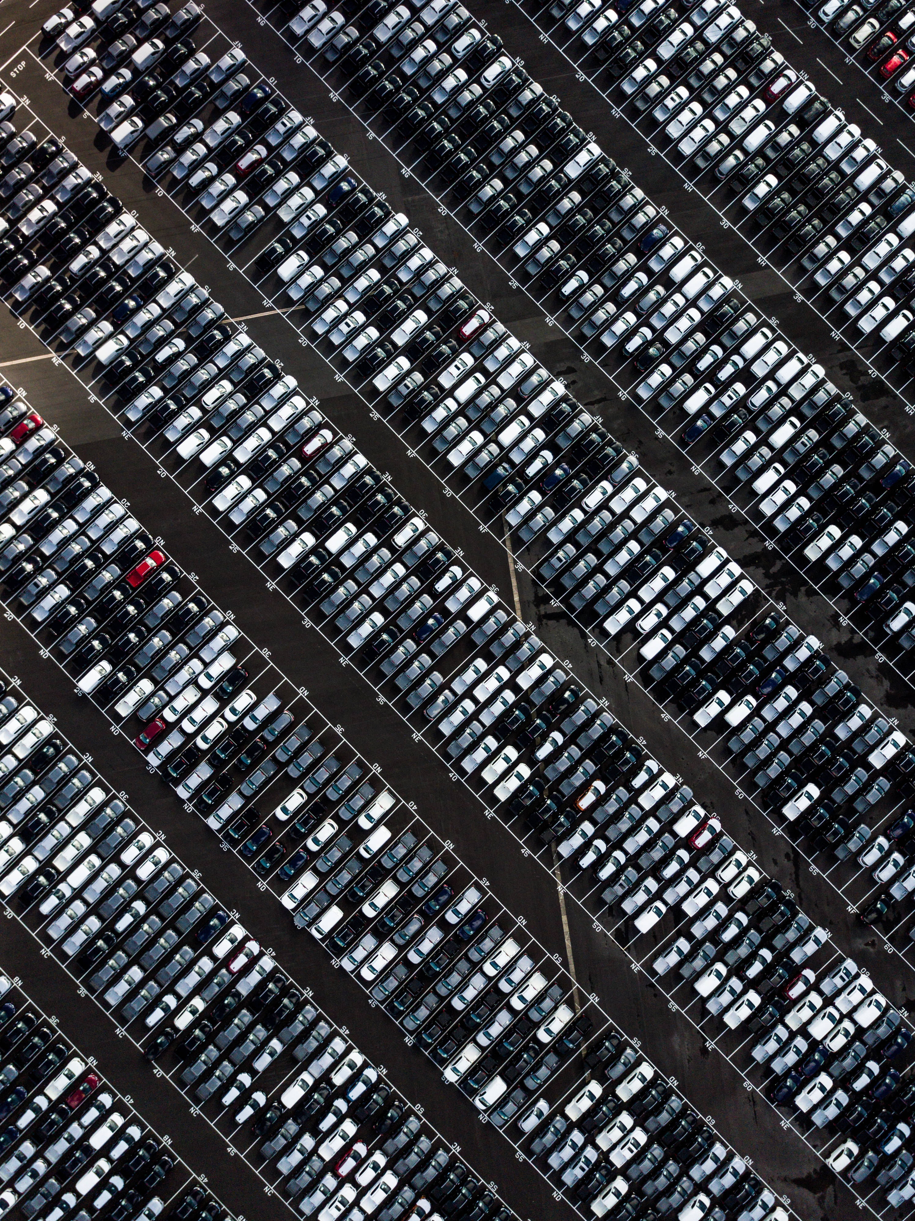 黑色安卓 桌布 壁紙 — 廣闊停車場的鳥瞰圖，整齊排列的汽車行列，主要是白色和黑色，帶有少量紅色點綴。