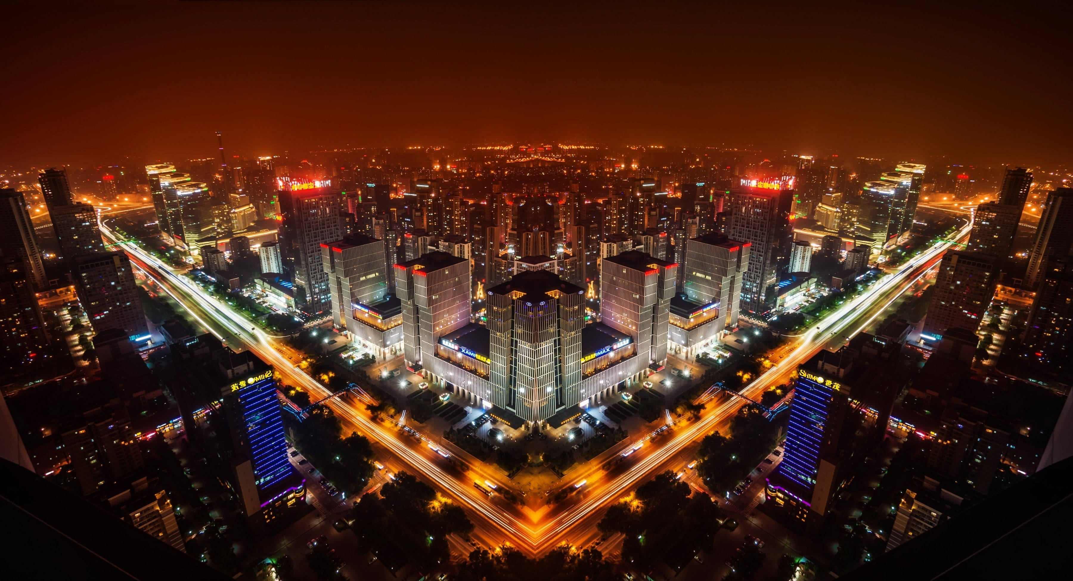 Beijing 桌布 壁紙 — 廣闊城市景觀的夜間航拍，閃爍的摩天大樓和車流形成的光跡。