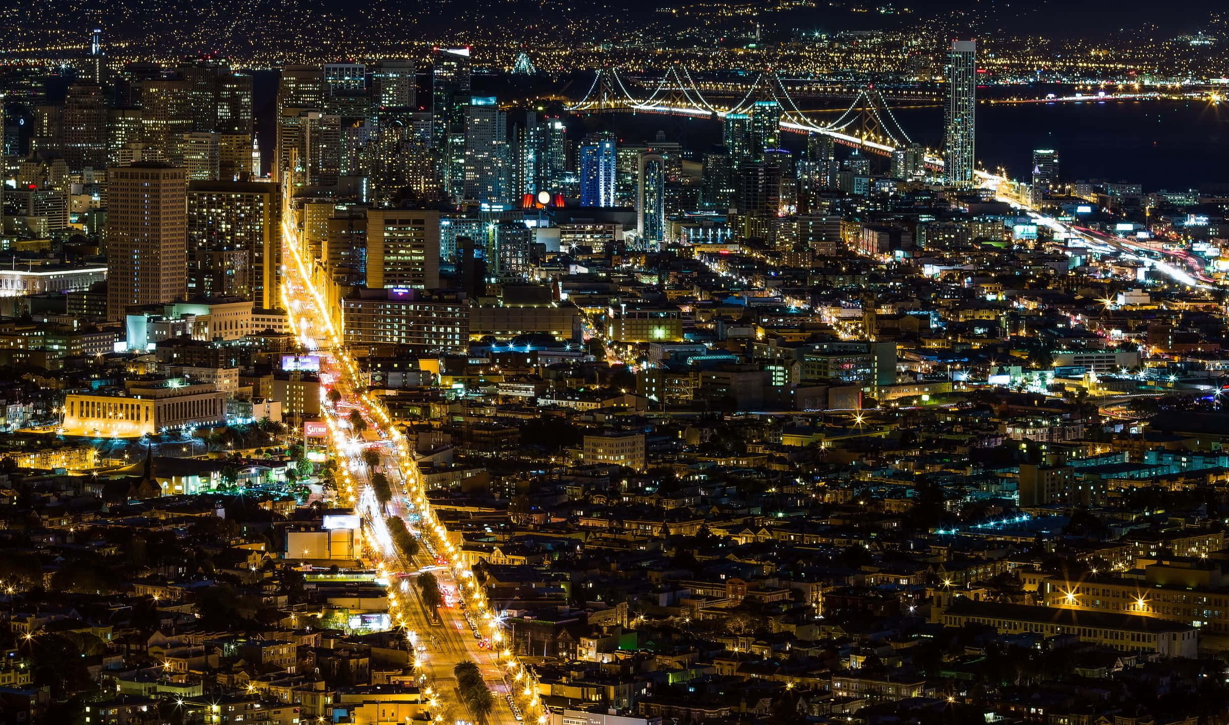 2440x1440 San Francisco 桌布 壁紙 — 廣闊城市景觀的空中夜景，閃爍的摩天大樓和橫跨黑暗水道的燈光橋樑。