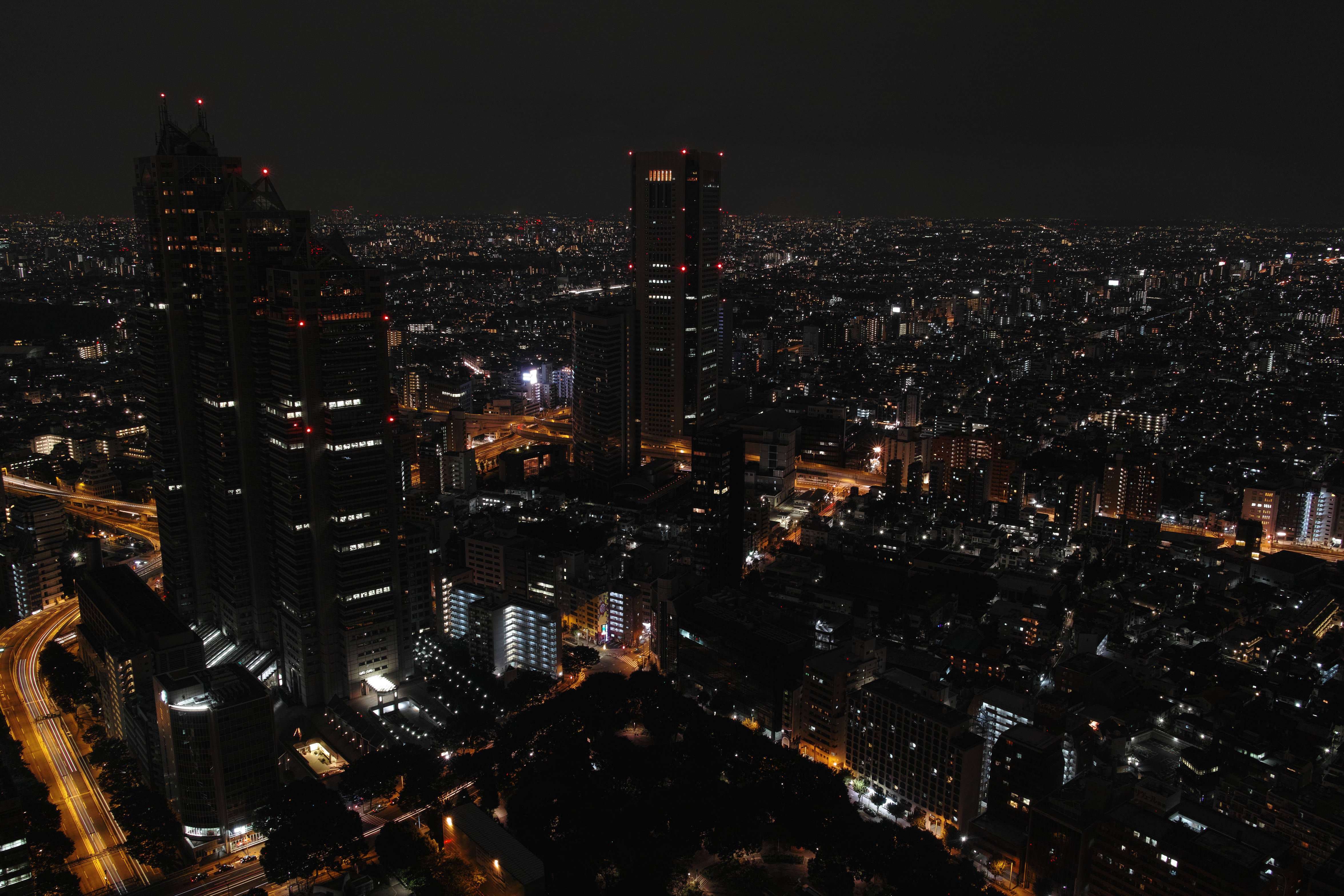 東京 桌布 壁紙 — 廣闊城市景觀的空中夜景，高聳的摩天大樓和下方發光的街道。