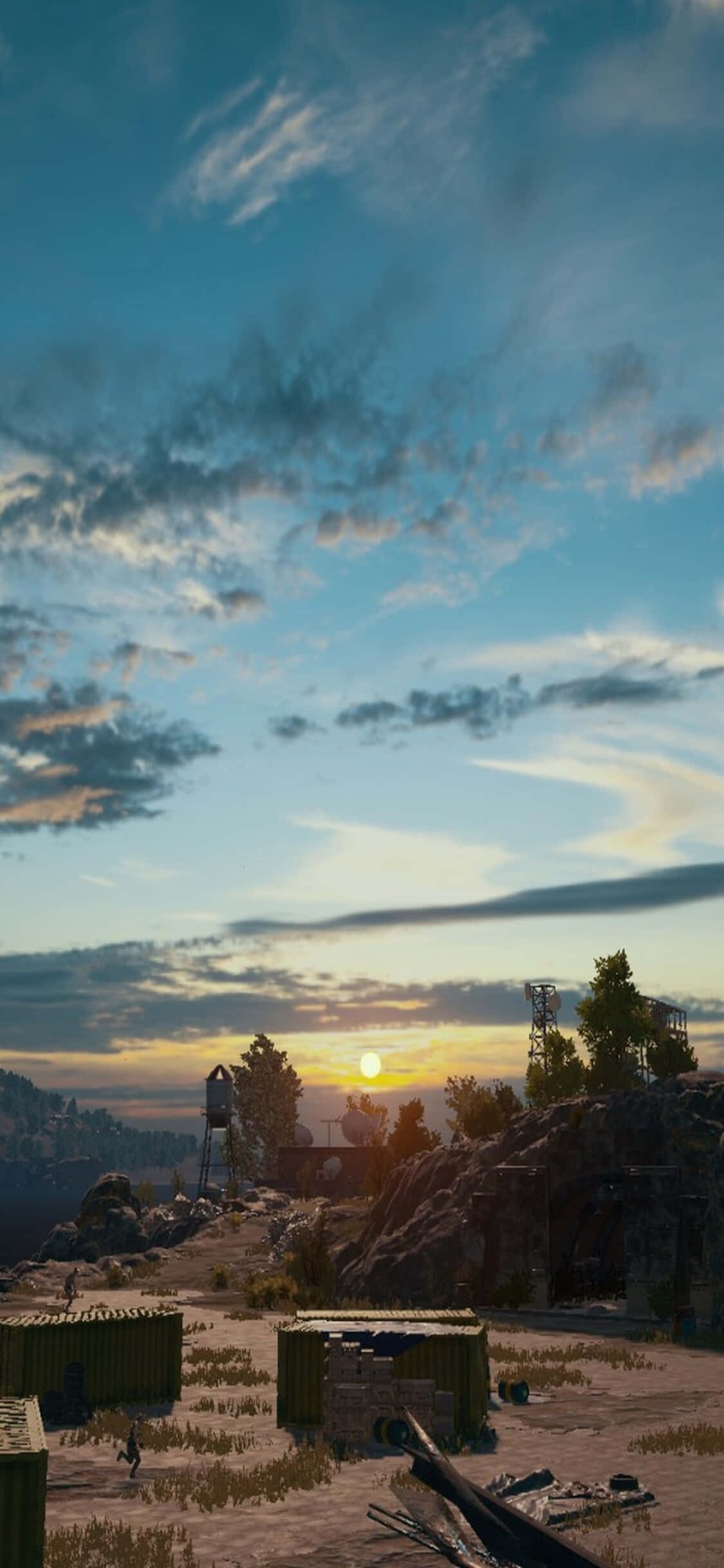Playerunknown's Battlegrounds 桌布 壁紙 — 廣闊多雲的天空下，崎嶇的沙漠景觀上散落著工業集裝箱和岩石露頭，夕陽西下。